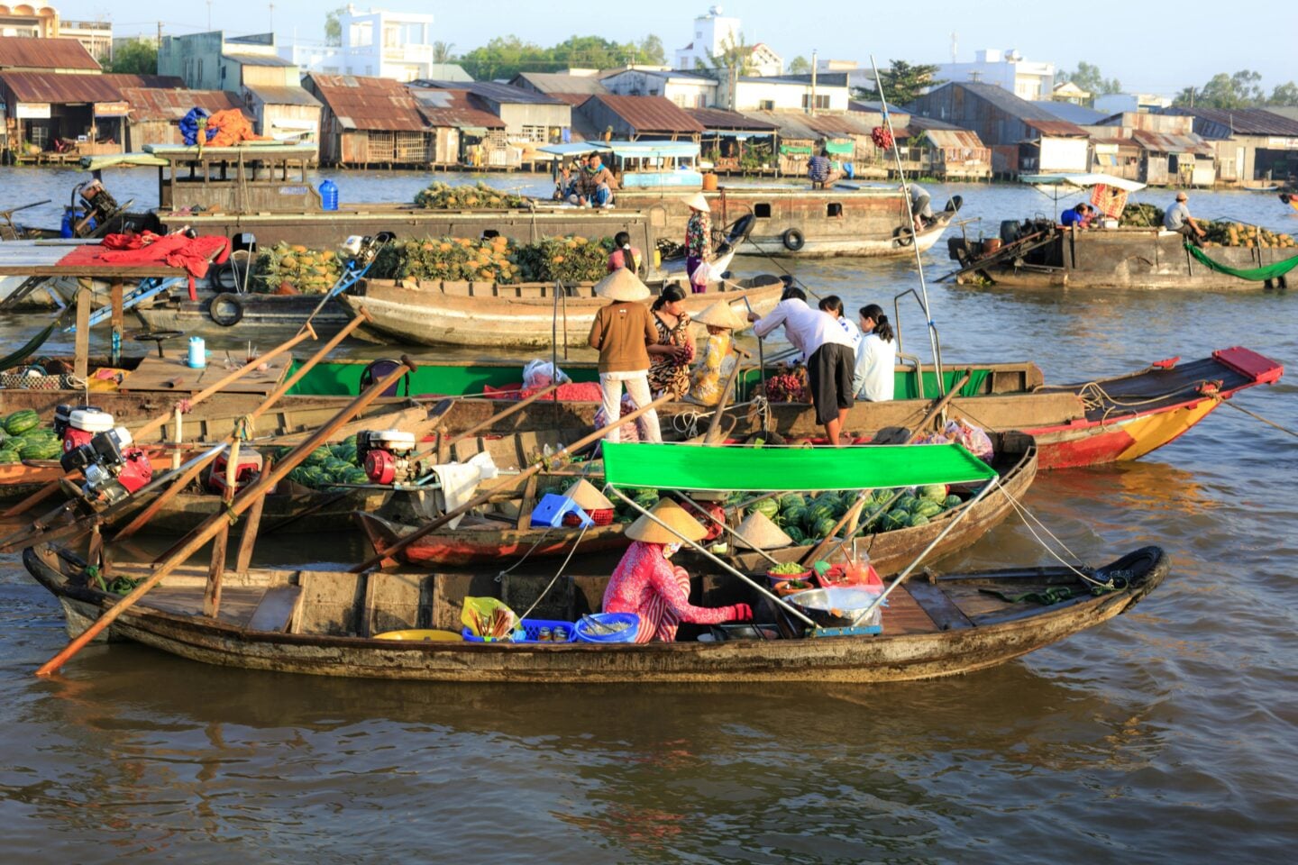 Floating market boats loaded with fruit and produce at sunrise on the Mekong River in Can Tho, Vietnam.