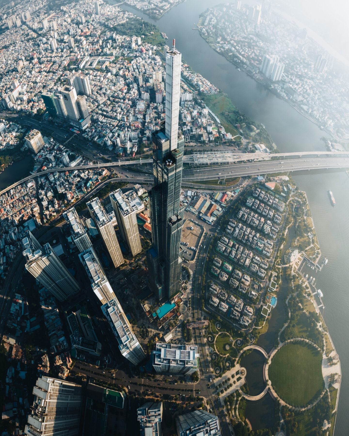 Aerial view of Ho Chi Minh City, Vietnam, featuring Landmark 81 skyscraper surrounded by dense urban neighborhoods and the Saigon River.