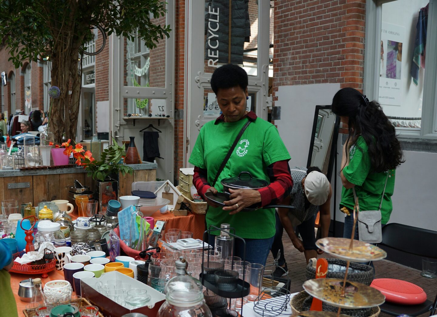 People browsing second-hand household items at a reuse market with kitchenware and decor