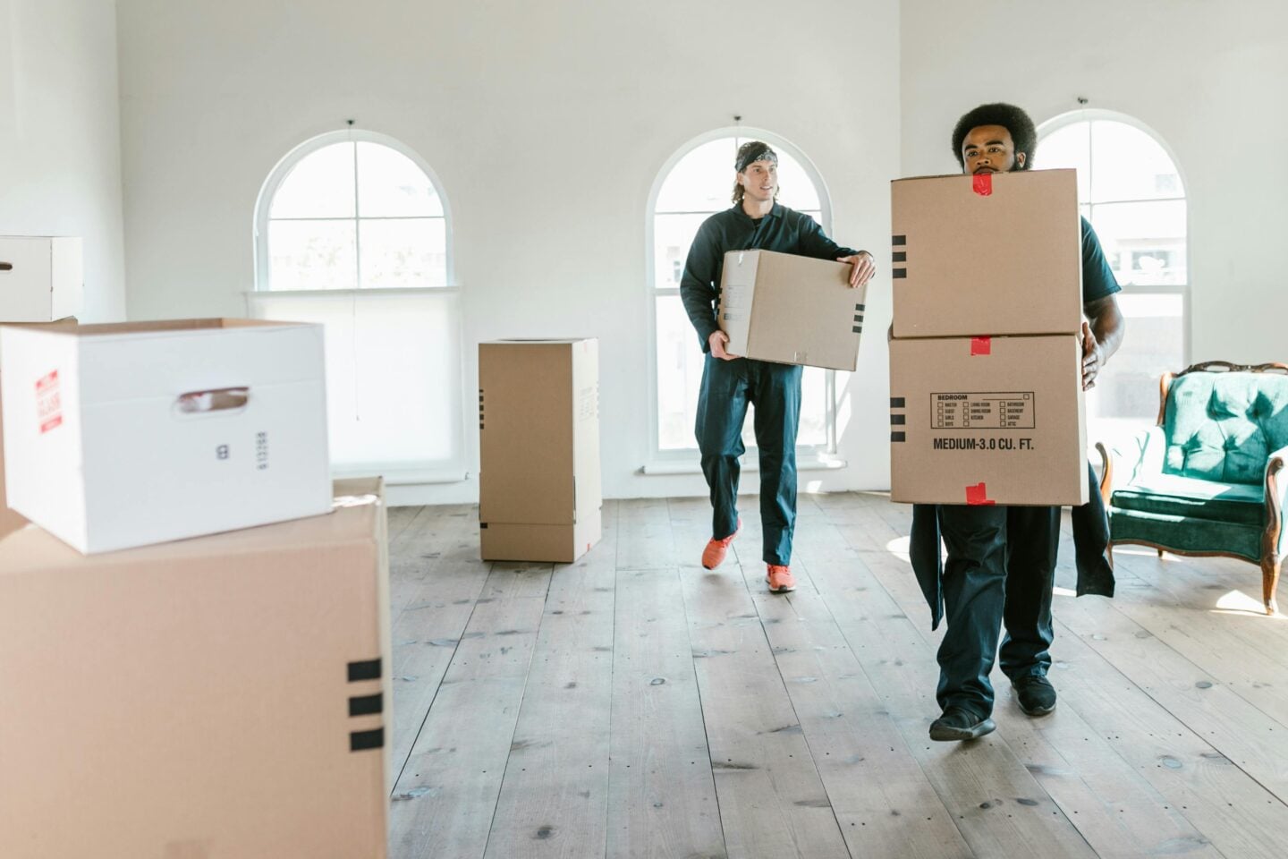 Professional movers carrying cardboard boxes into an empty room during a house move, helping keep the relocation process smooth and organized.