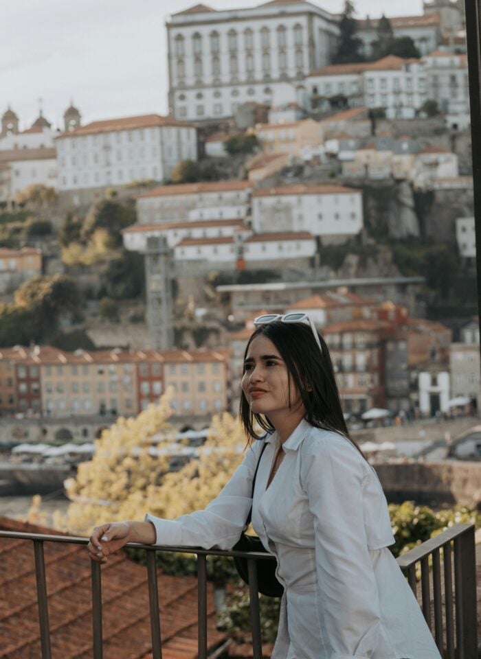 Woman standing at a scenic viewpoint overlooking the historic riverside buildings of Porto, Porto District, Portugal.