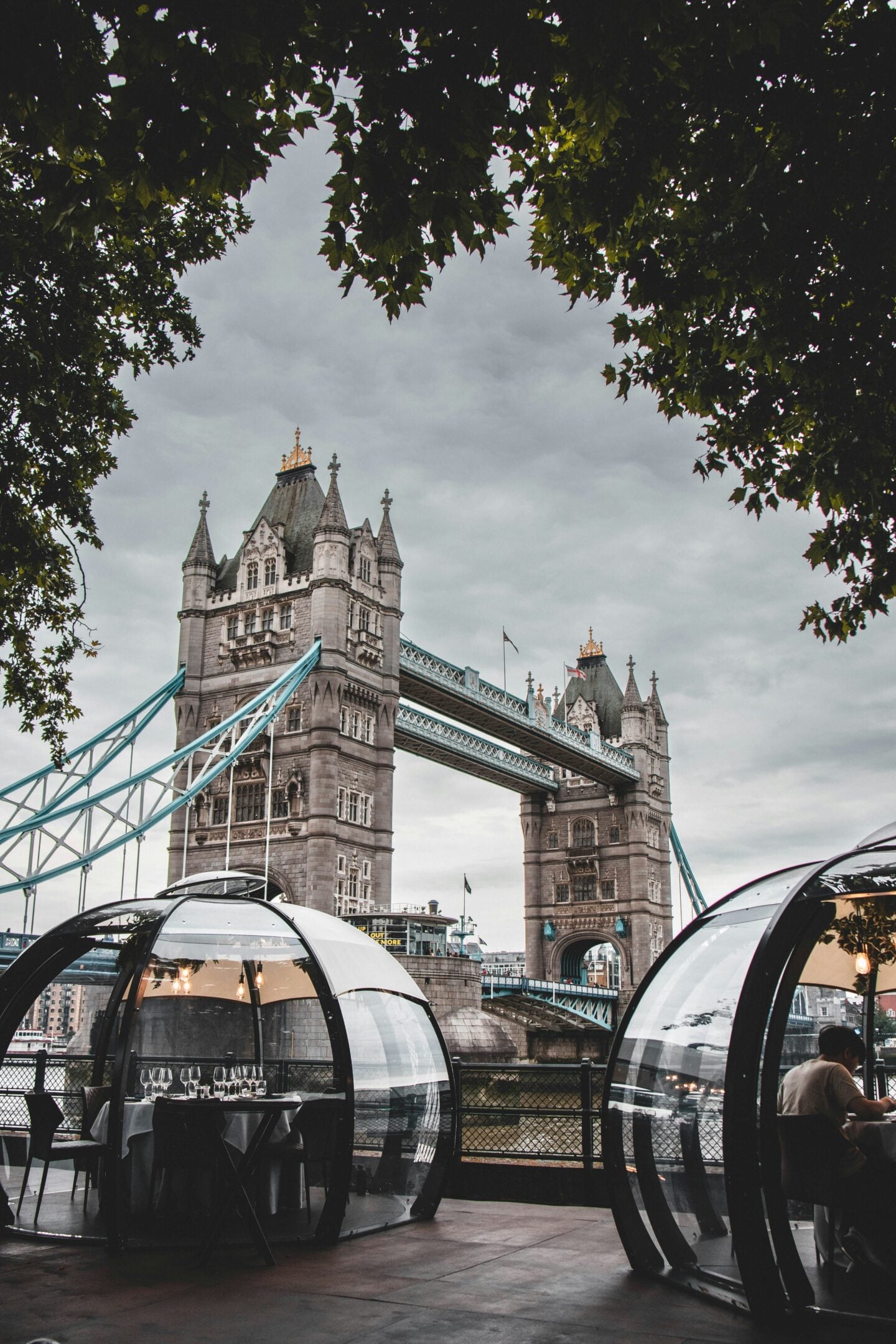 Heated riverside dining igloos next to Tower Bridge in London, a cozy winter experience with stunning views.