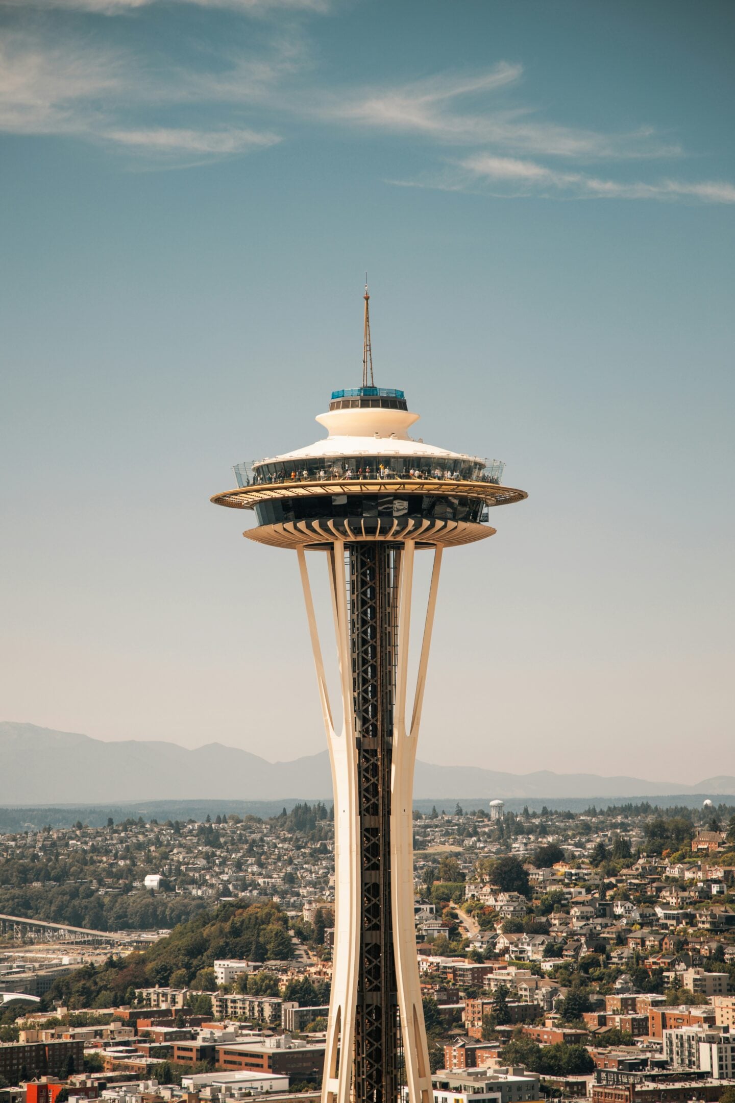 A detailed view of the Space Needle observation deck rising above Seattle’s residential neighborhoods and distant mountains.