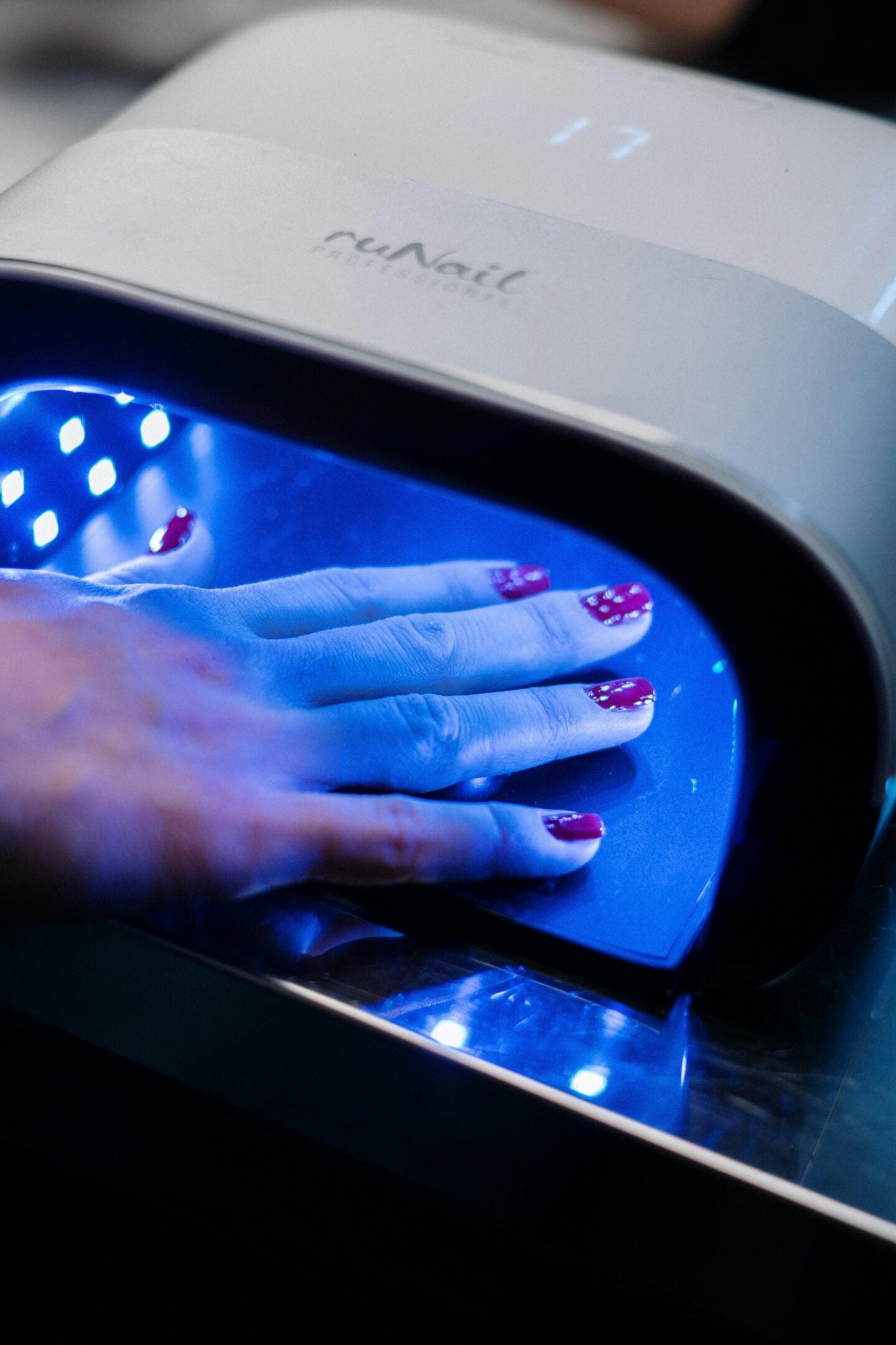 A person curing their gel manicure under a UV LED nail lamp during a professional nail treatment.