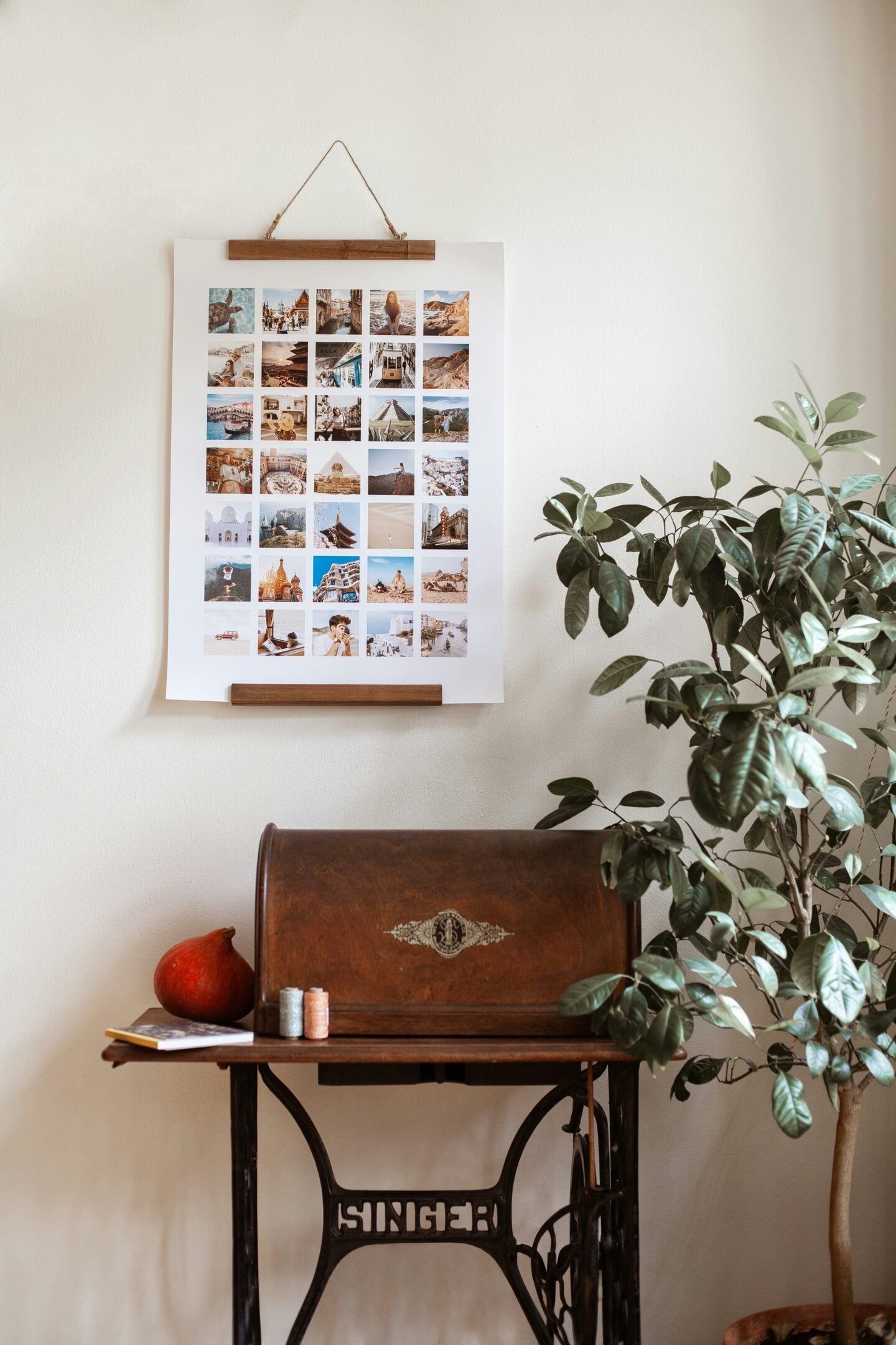 Framed travel photo collage hanging on a wall above a vintage sewing table, with a houseplant beside it, creating a cozy travel-inspired interior.