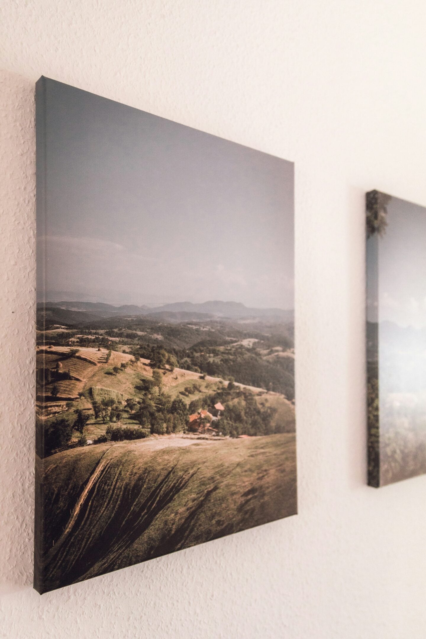Canvas wall art displaying a panoramic countryside landscape with rolling hills, photographed from a side angle to show depth and texture.