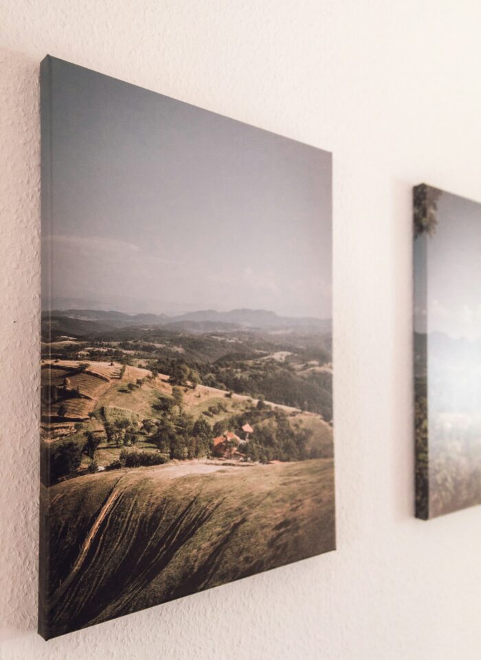 Canvas wall art displaying a panoramic countryside landscape with rolling hills, photographed from a side angle to show depth and texture.