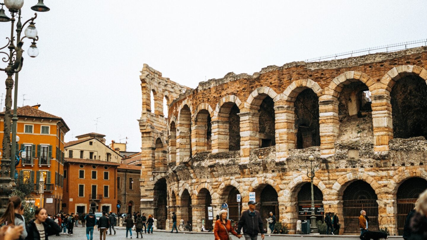 Ancient Roman amphitheater Verona Arena surrounded by city streets and visitors in Verona, Italy