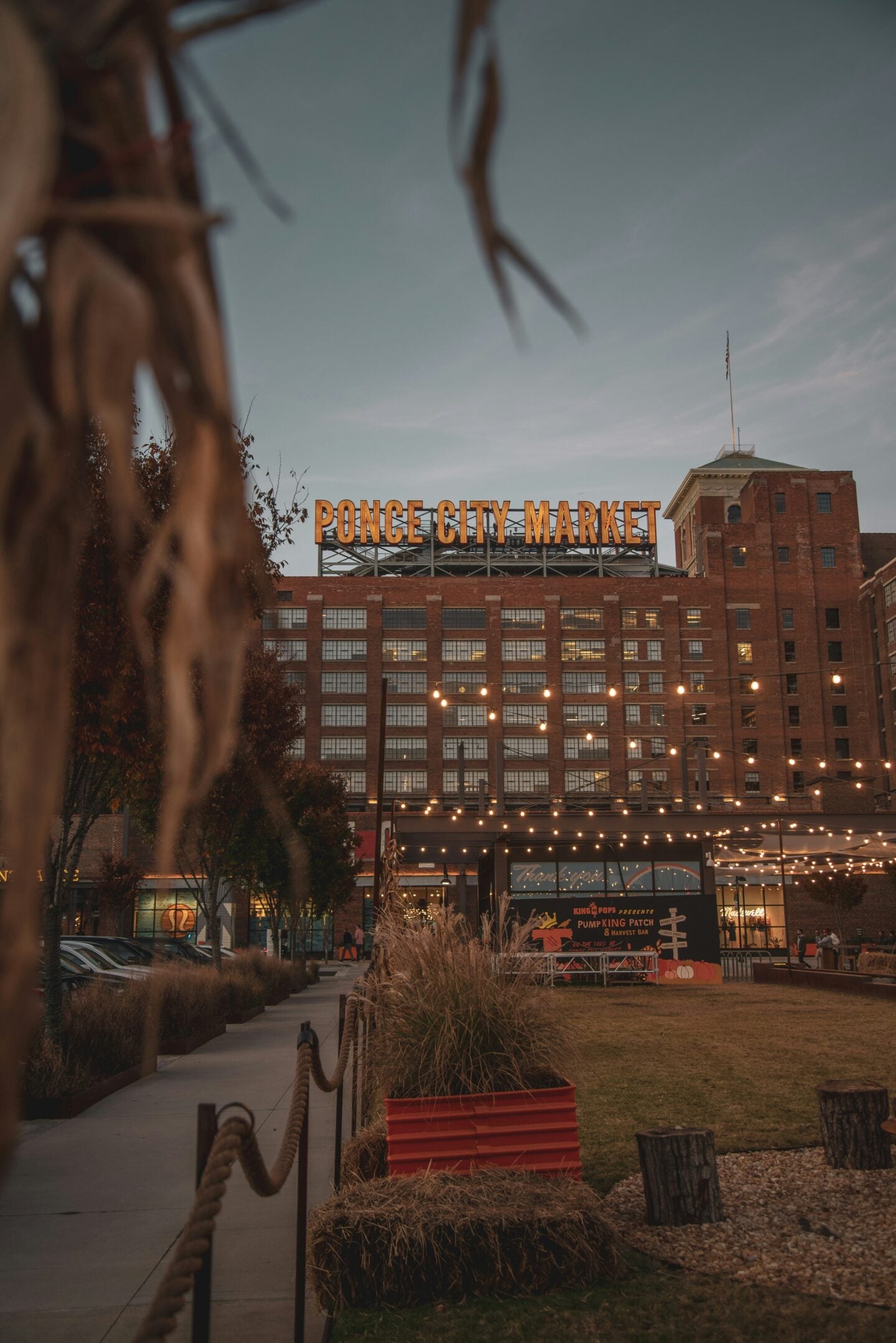 Exterior view of Ponce City Market in Atlanta at dusk, with string lights and people walking by.