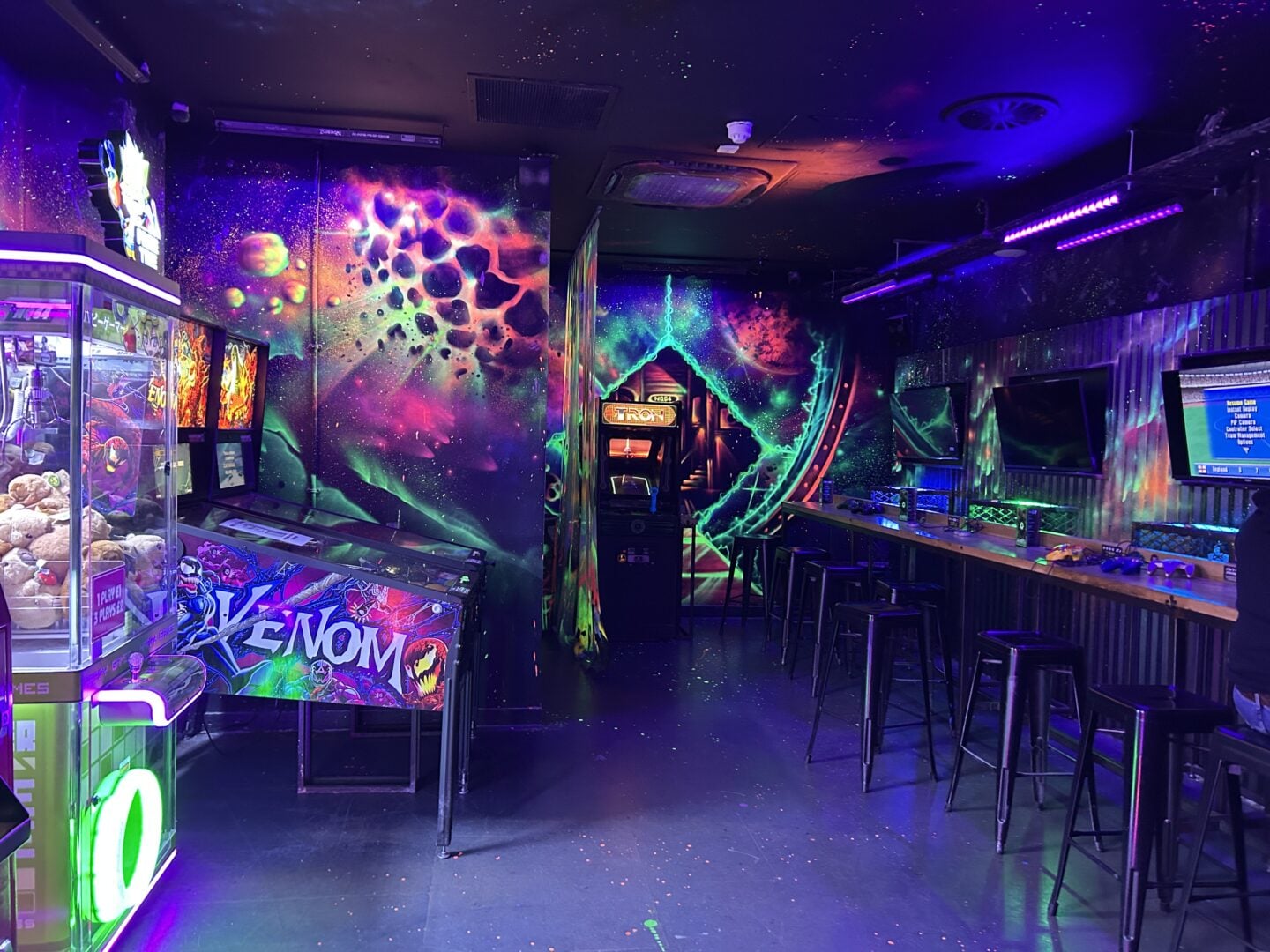 Neon-lit interior of NQ64 arcade bar in Soho, featuring retro games and vibrant murals—a fun indoor winter activity in London.