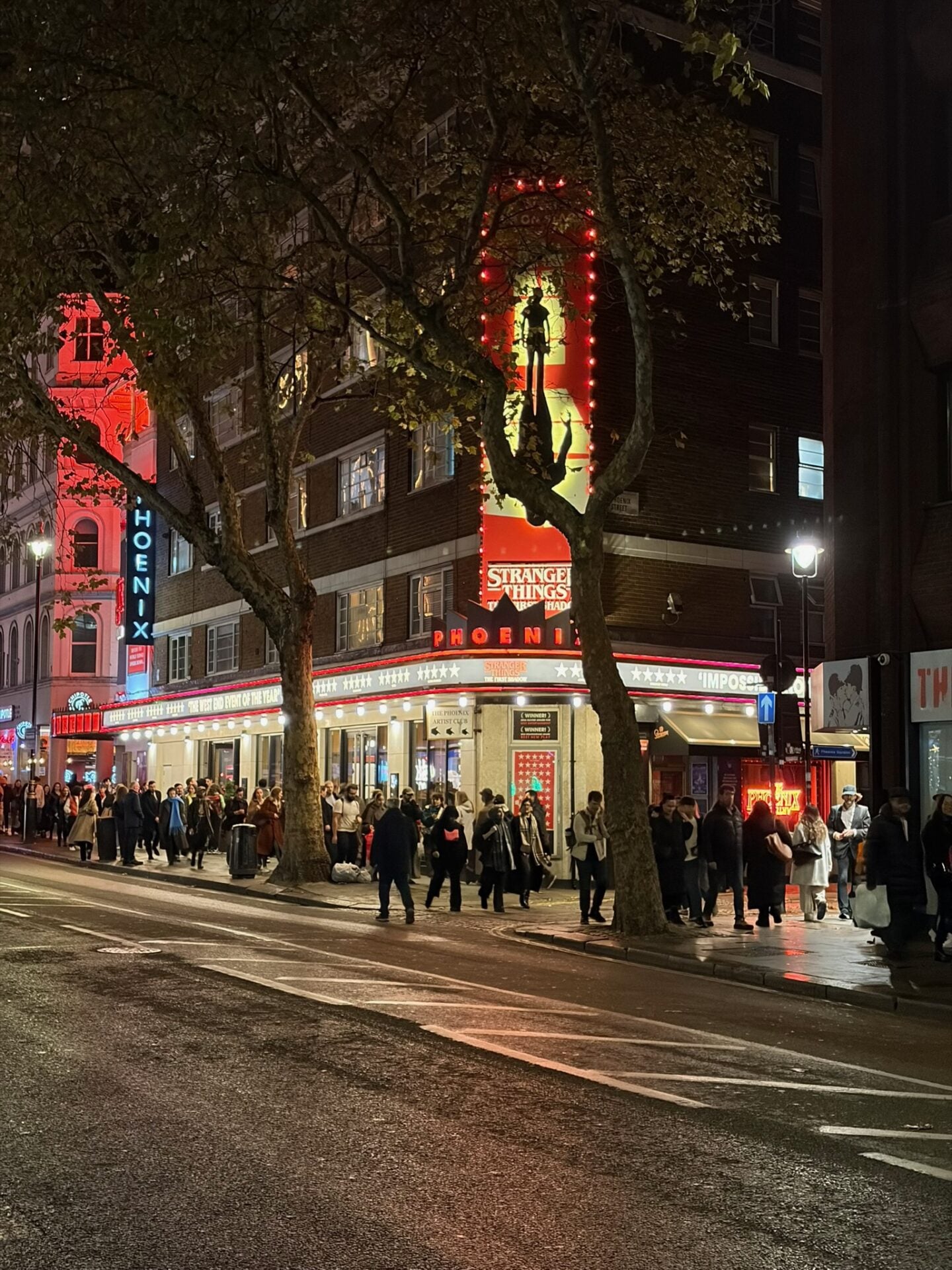 The Phoenix Theatre in London illuminated at night for Stranger Things: The First Shadow, a popular winter West End show with crowds lining the street.