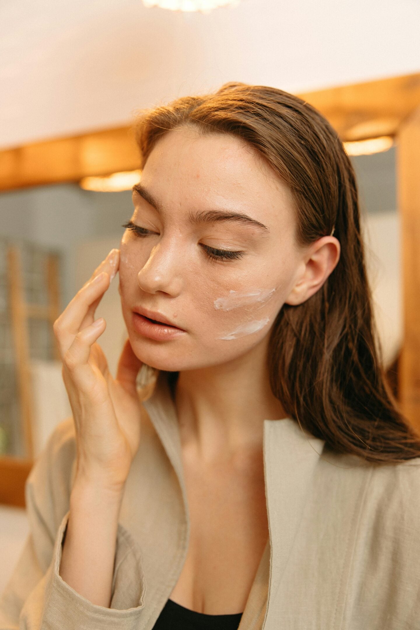 A woman gently applying moisturizer to her face as part of her skincare routine.