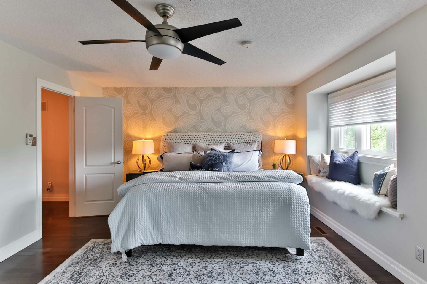 Modern bedroom with double bed, ceiling fan, bedside lamps, and neutral decor