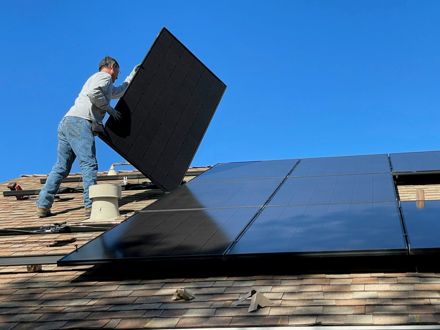 Worker installing solar panels on a residential rooftop