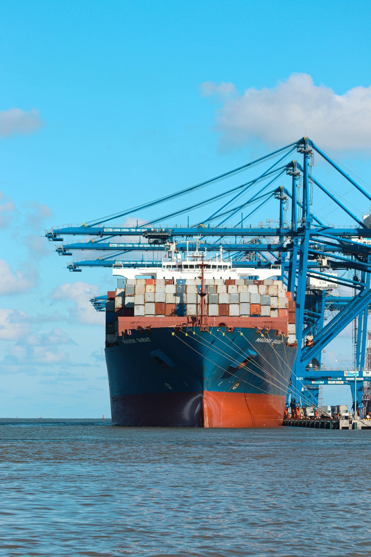 Large cargo ship docked at a port with stacked shipping containers and cranes, representing international trade and imports.