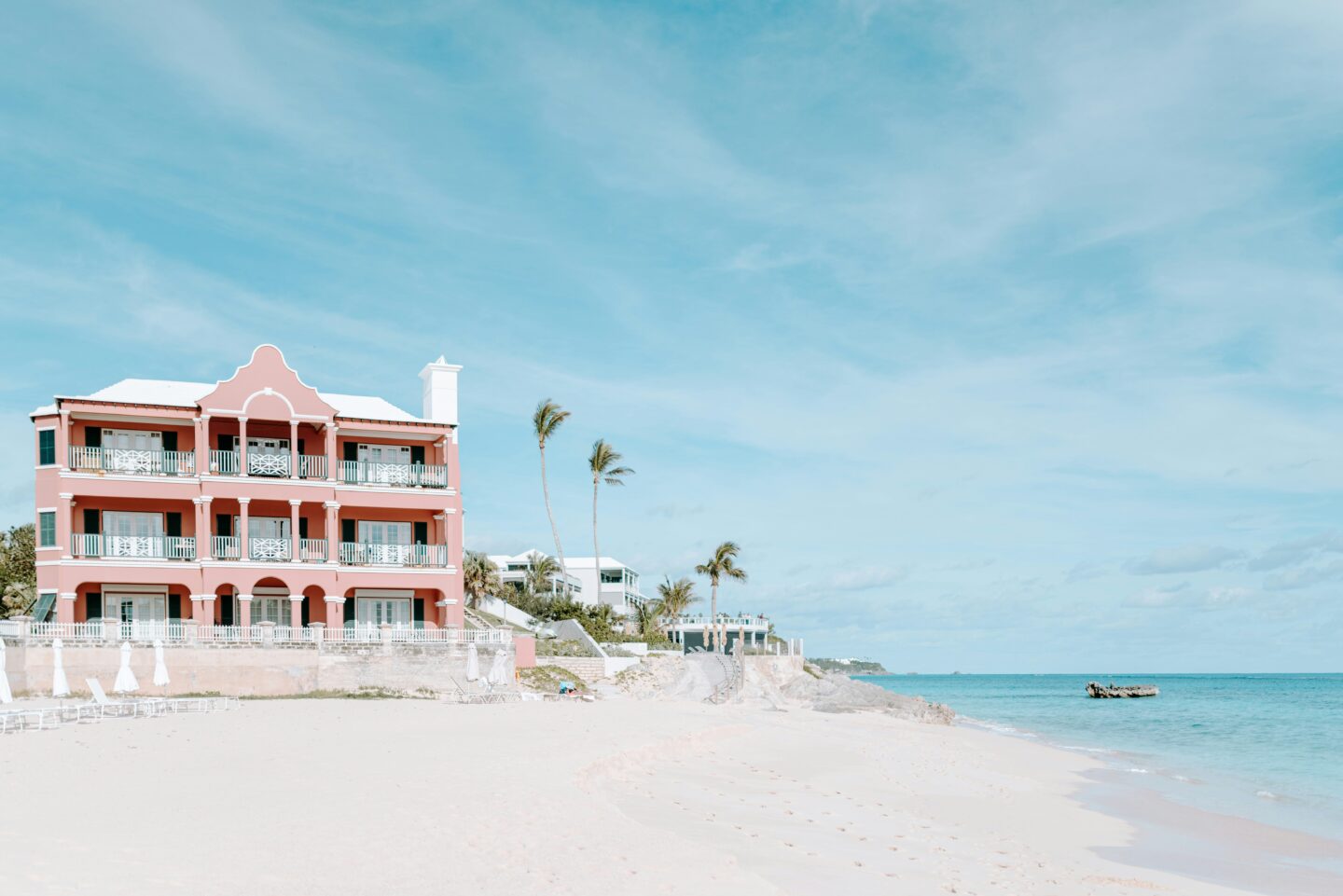 Pastel pink beachfront building with palm trees along the coast of Bermuda