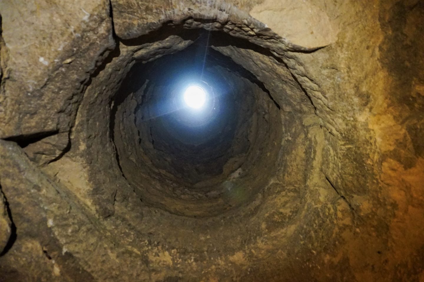 Vertical stone shaft inside the Paris Catacombs with light shining from above, reflecting the descent and isolation themes of As Above, So Below.