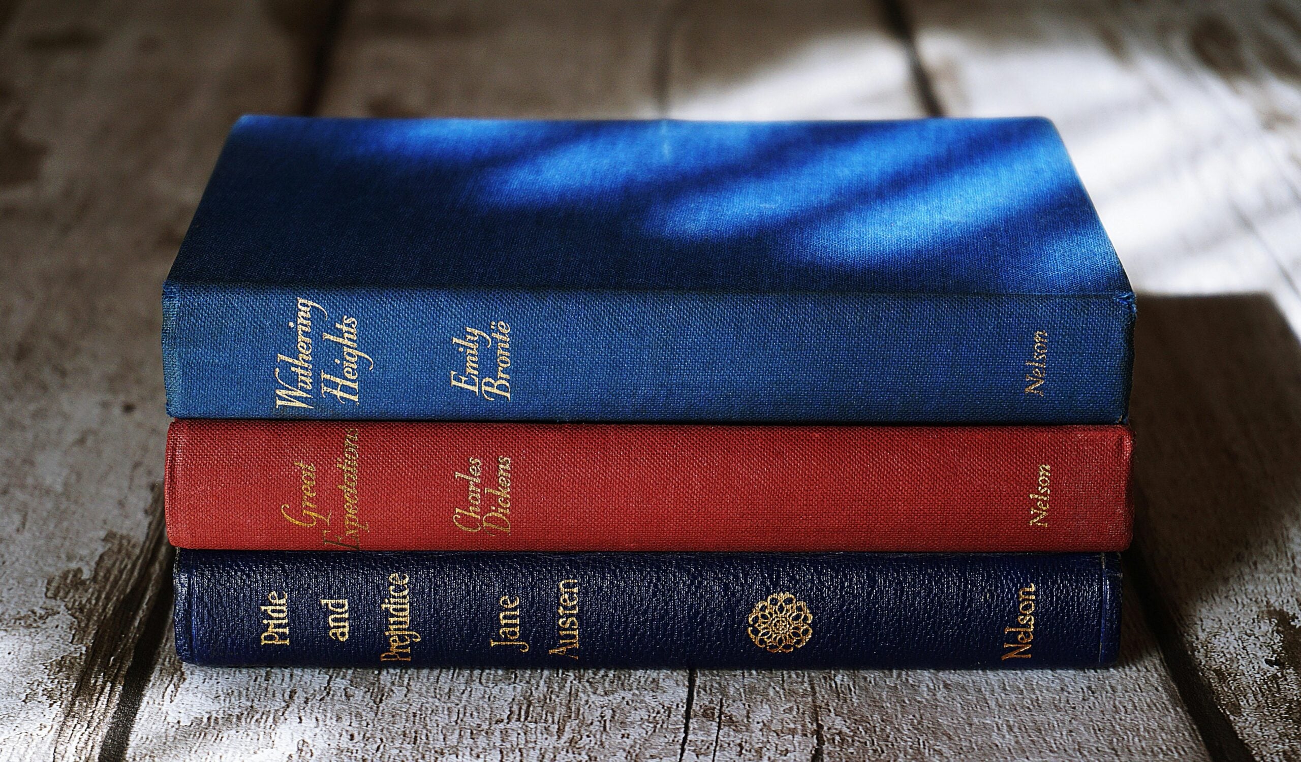 Stack of three classic hardcover books on a wooden surface, including Wuthering Heights, Great Expectations, and Pride and Prejudice, with cloth-bound covers and gold lettering.