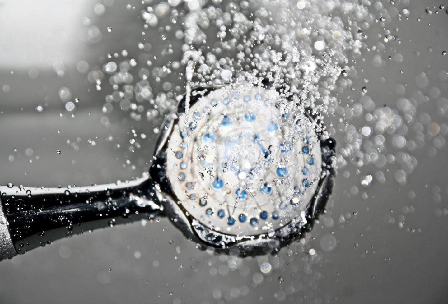 Close-up of a shower head spraying water in a bathroom
