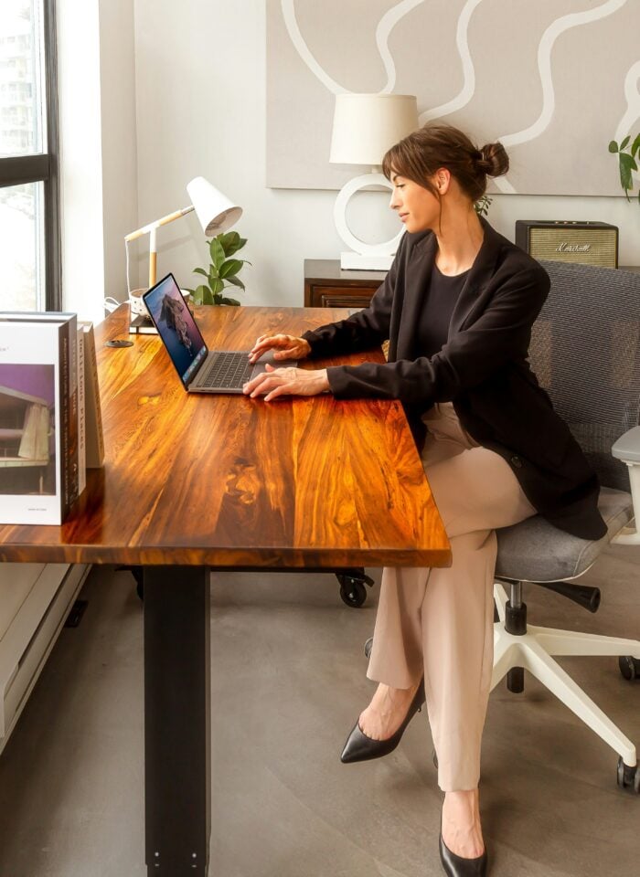 Professional woman working at a modern home office desk with a laptop, illustrating small business planning and financial organization.