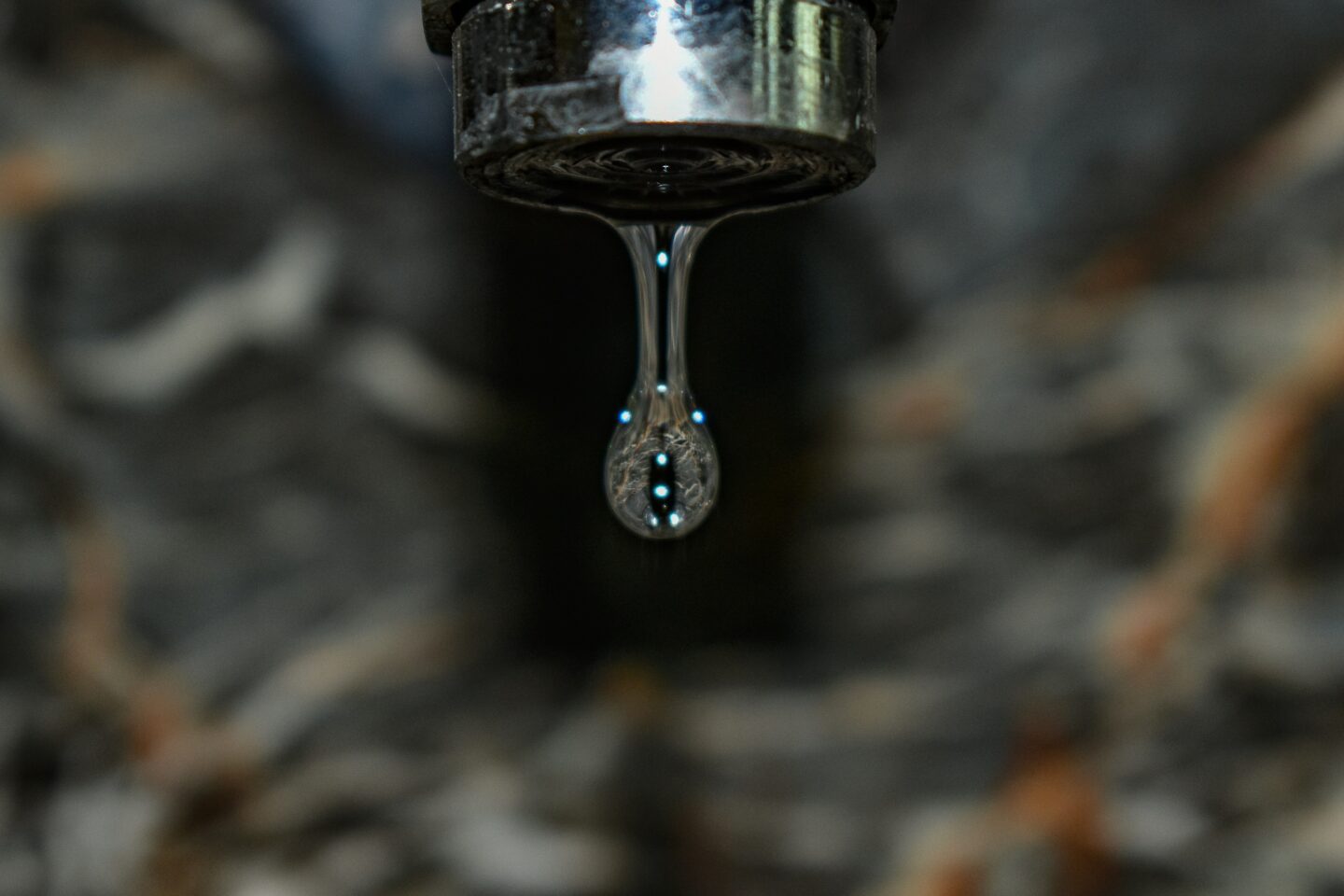 Close-up of a water faucet dripping, illustrating the practice of letting faucets drip to prevent frozen pipes in winter.