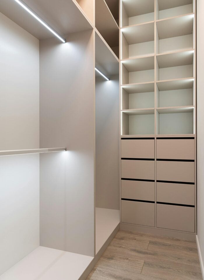 Custom walk-in closet storage system with shelving, drawers, and built-in lighting.