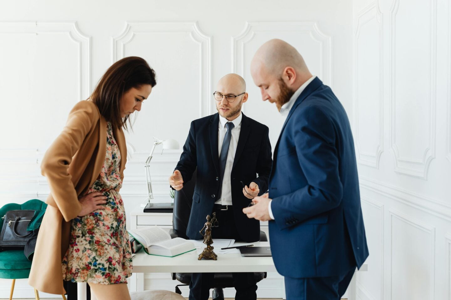 Couple standing with a divorce lawyer in an office, reviewing documents together at a desk during a legal consultation.