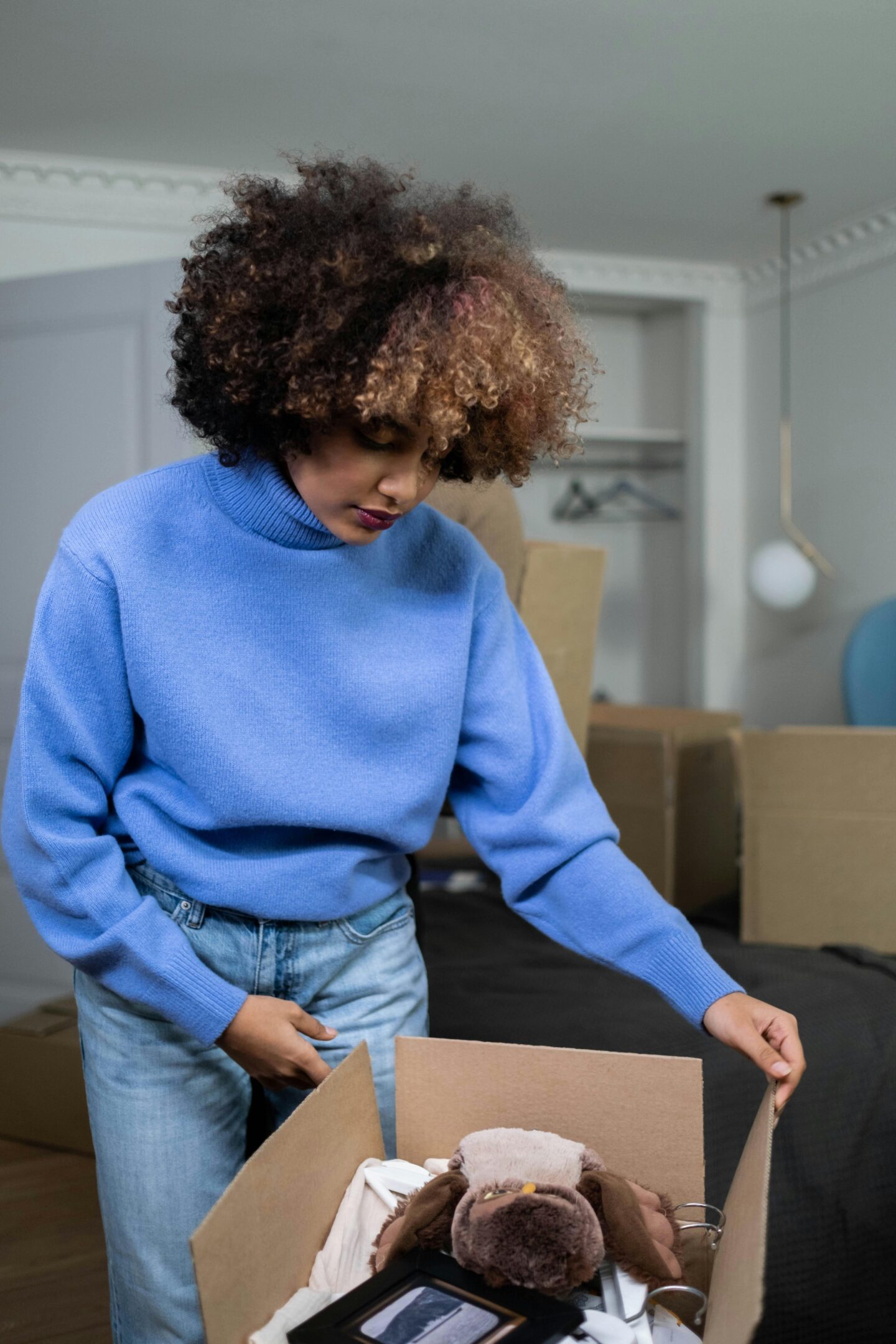 Woman packing belongings into a cardboard box during a home move, organizing personal items for a stress-free relocation.