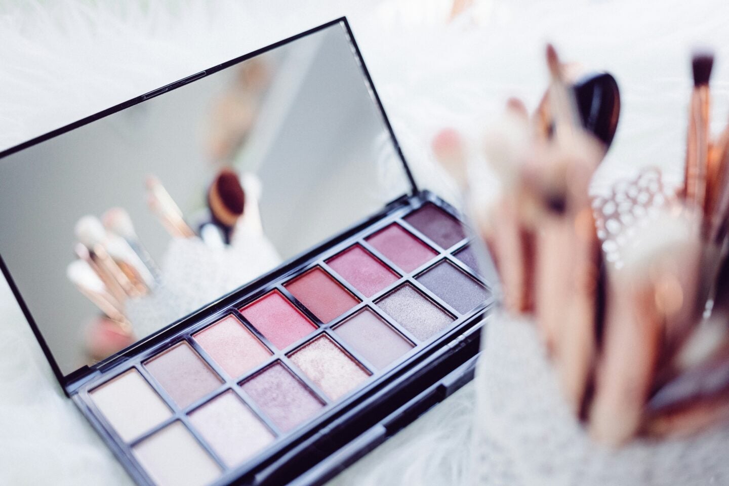 Soft pink and neutral eyeshadow palette with makeup brushes, romantic glam makeup setup for prom or special occasions.