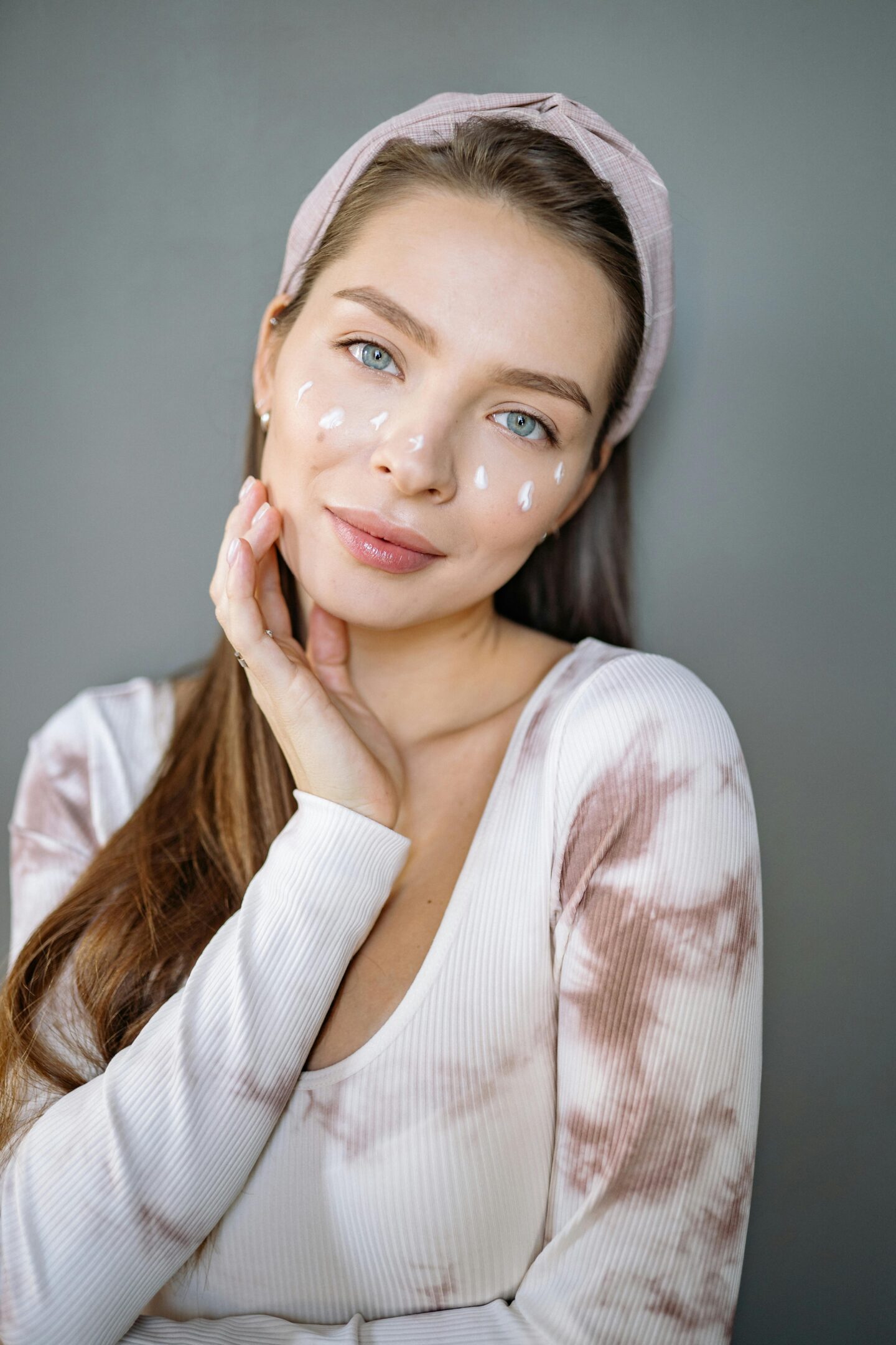 Woman applying facial skincare cream to her face.
