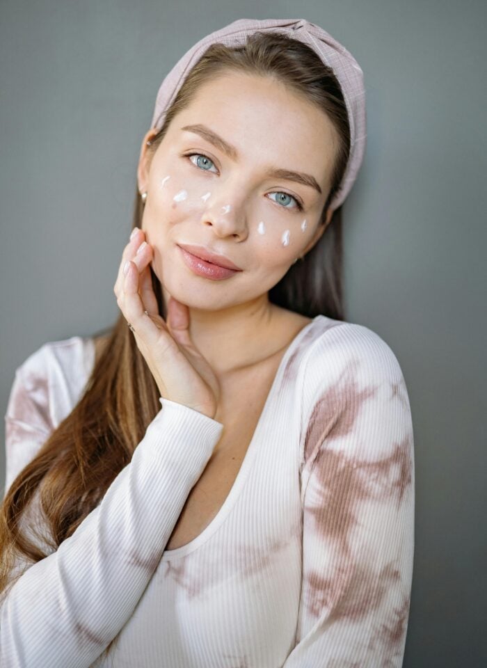 Woman applying facial skincare cream to her face.