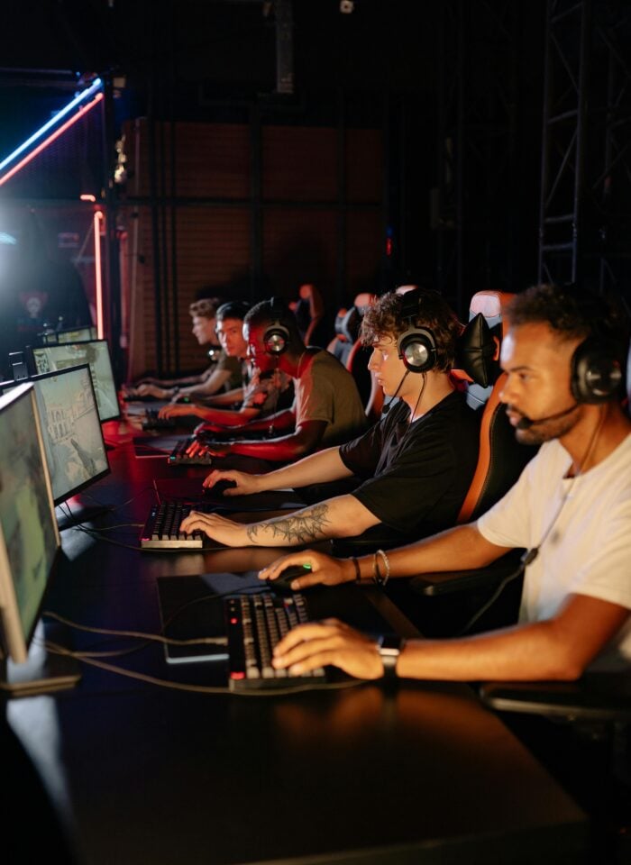 Team of esports players wearing headsets and competing at desktop gaming stations in a neon-lit tournament setup.