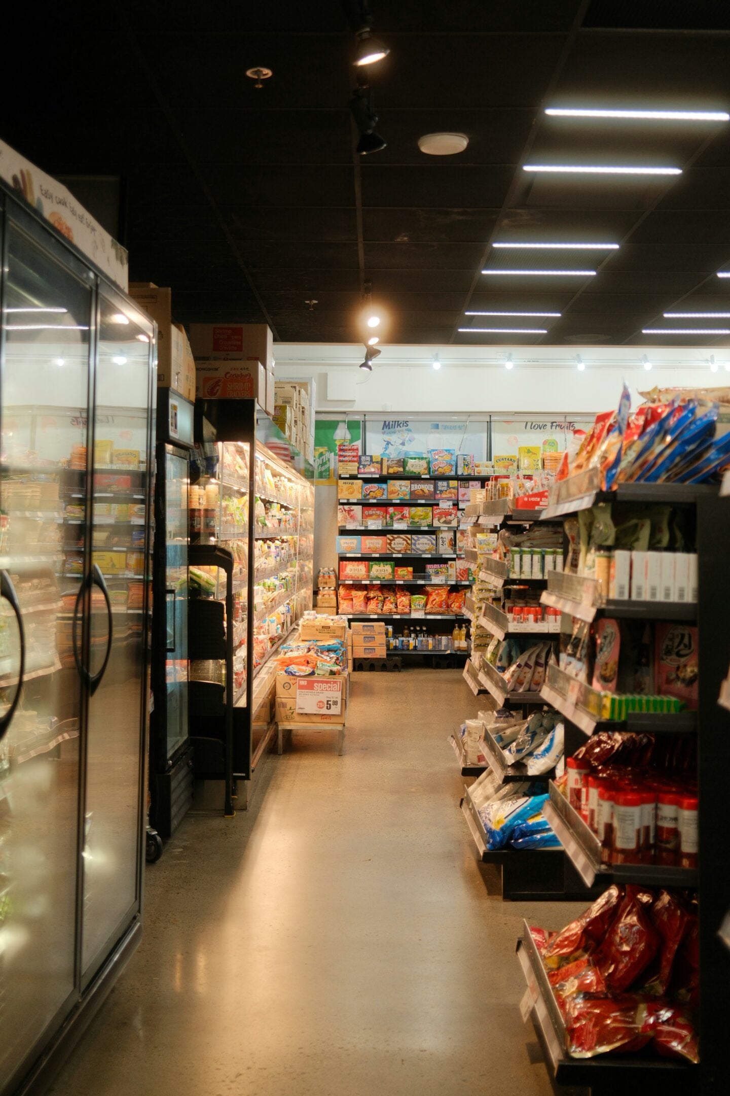Interior of a supermarket aisle showing packaged food products and refrigerated items.