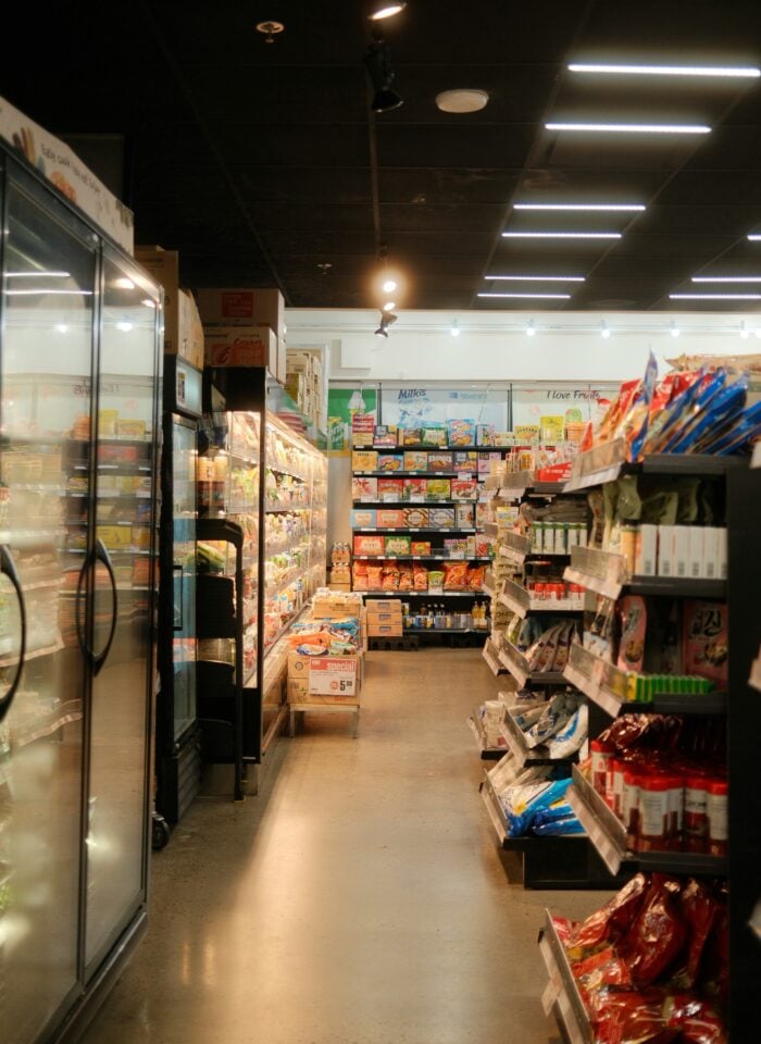 Interior of a supermarket aisle showing packaged food products and refrigerated items.