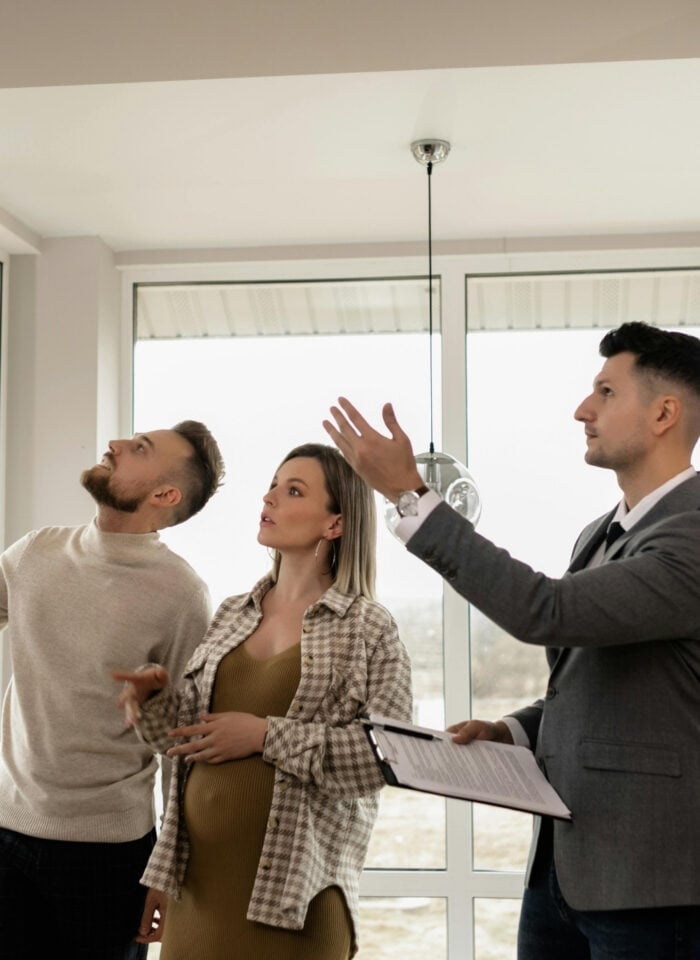 Real estate agent showing a modern apartment to a young couple during a home viewing.