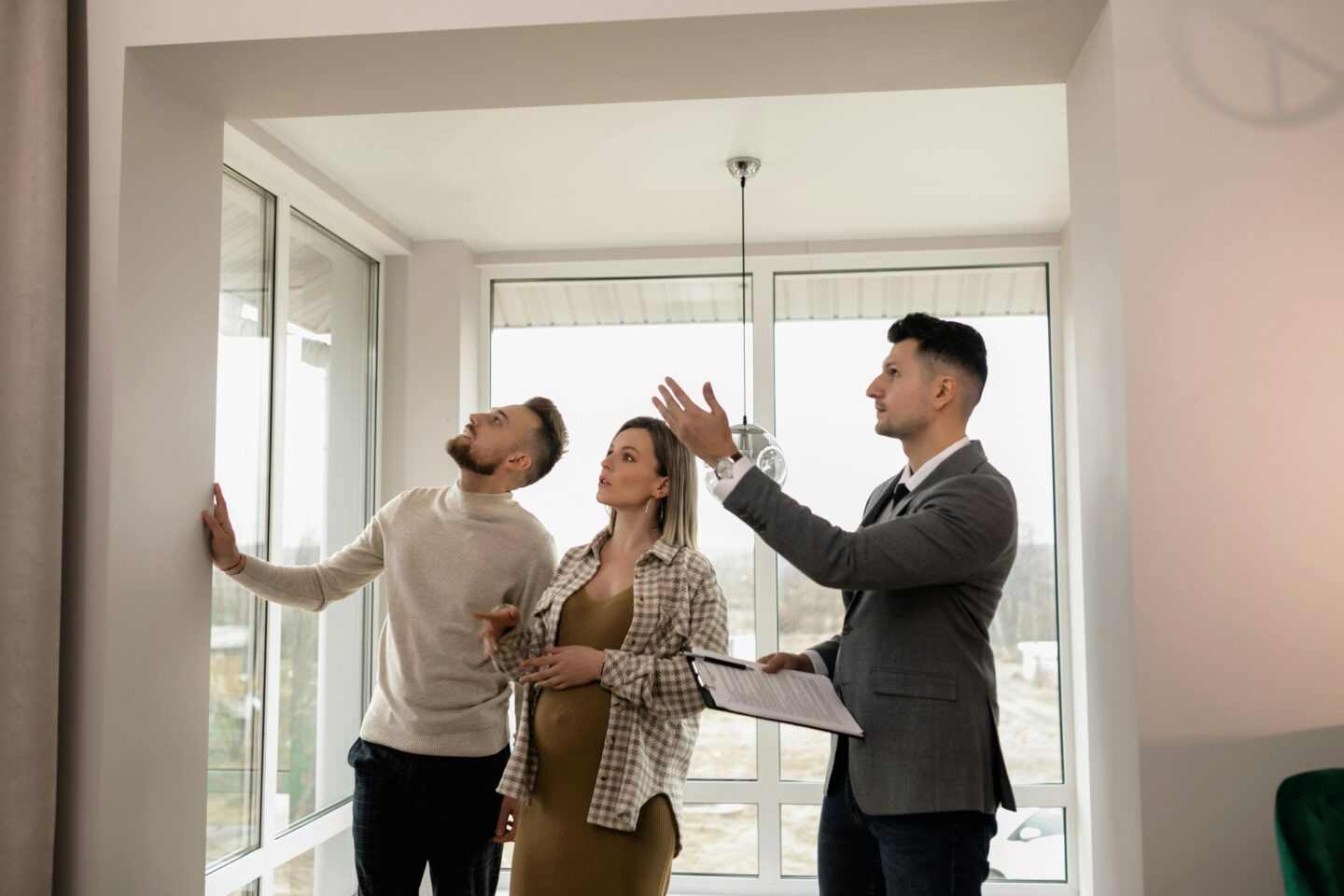 Real estate agent showing a modern apartment to a young couple during a home viewing.