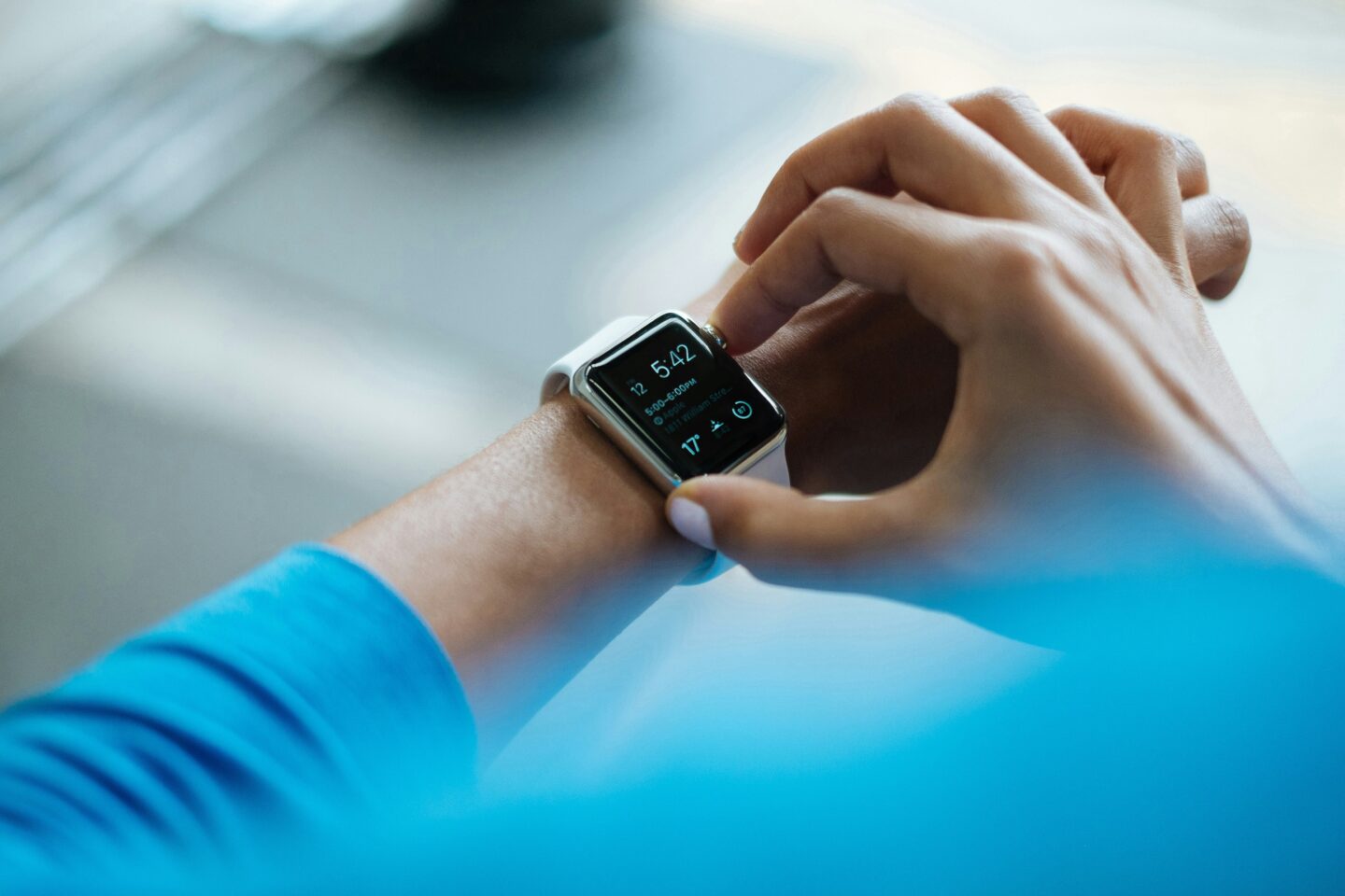 Person checking notifications on a smartwatch with a digital display while wearing a blue sleeve.