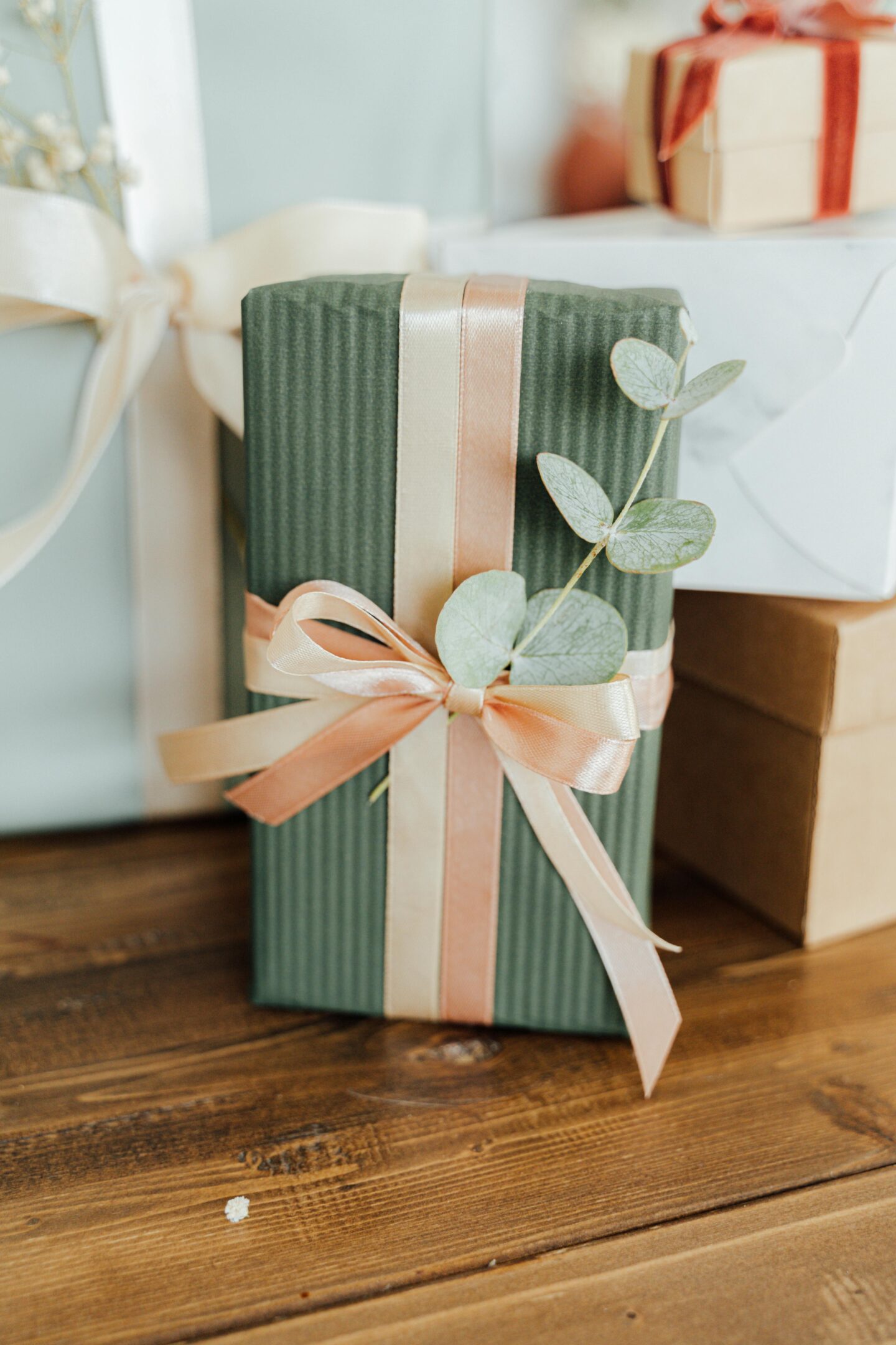 Elegant wedding gift box wrapped in green paper with satin ribbon and eucalyptus detail, perfect present idea for newlyweds.