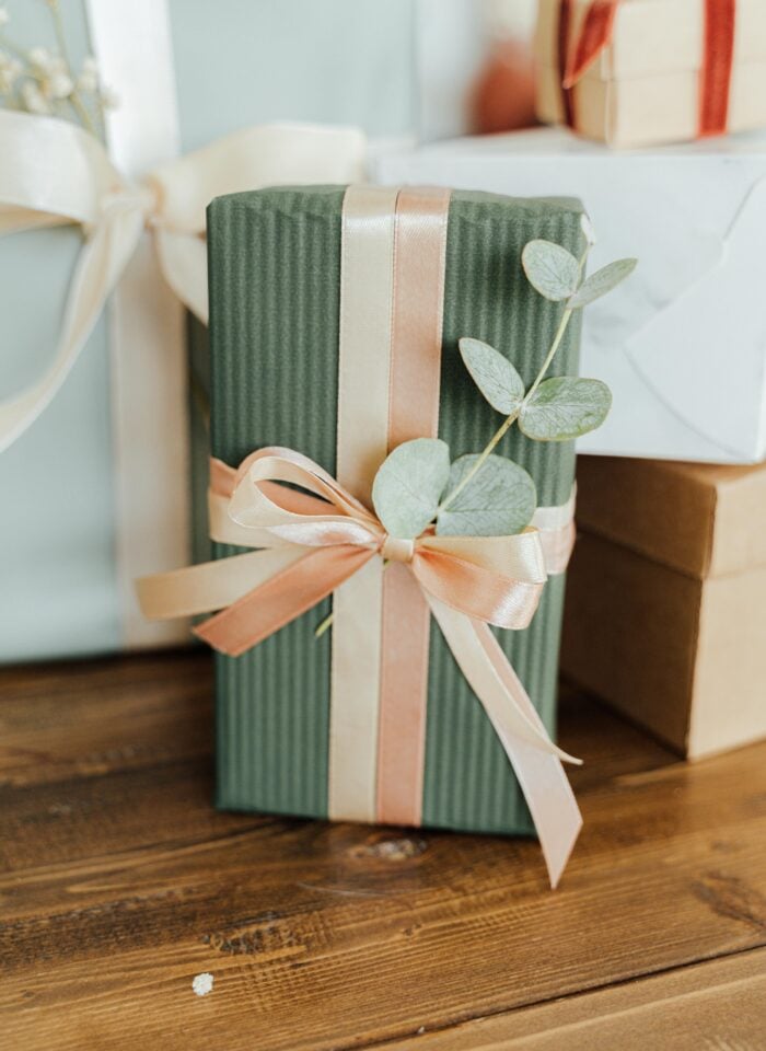 Elegant wedding gift box wrapped in green paper with satin ribbon and eucalyptus detail, perfect present idea for newlyweds.