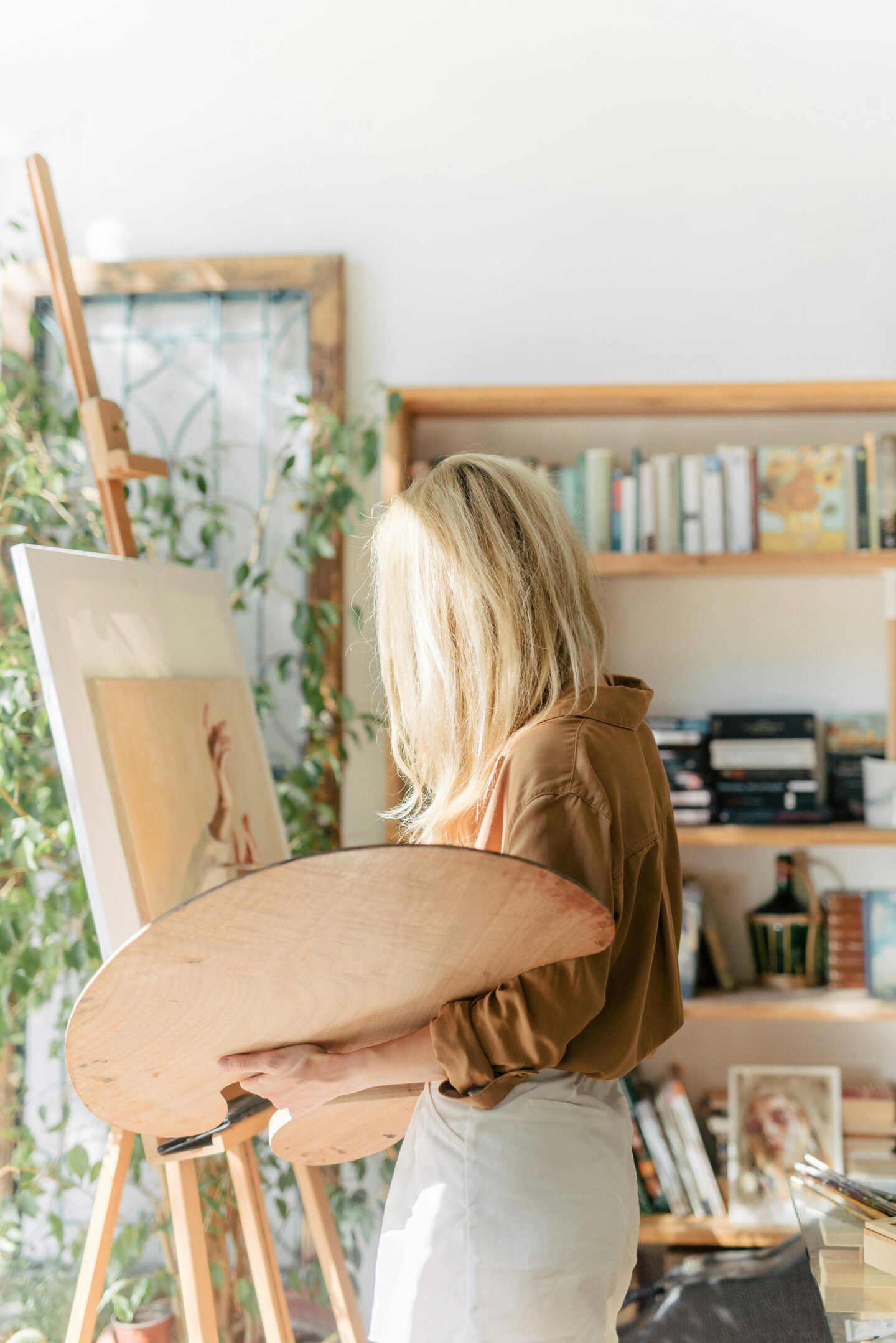 Woman painting on canvas in a bright home studio, symbolizing a custom artwork wedding gift for the happy couple.