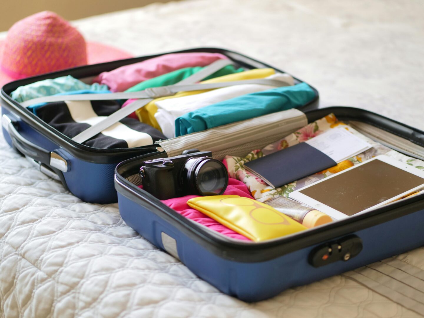 Open suitcase with colorful clothes camera passport and travel essentials packed for a beach vacation 