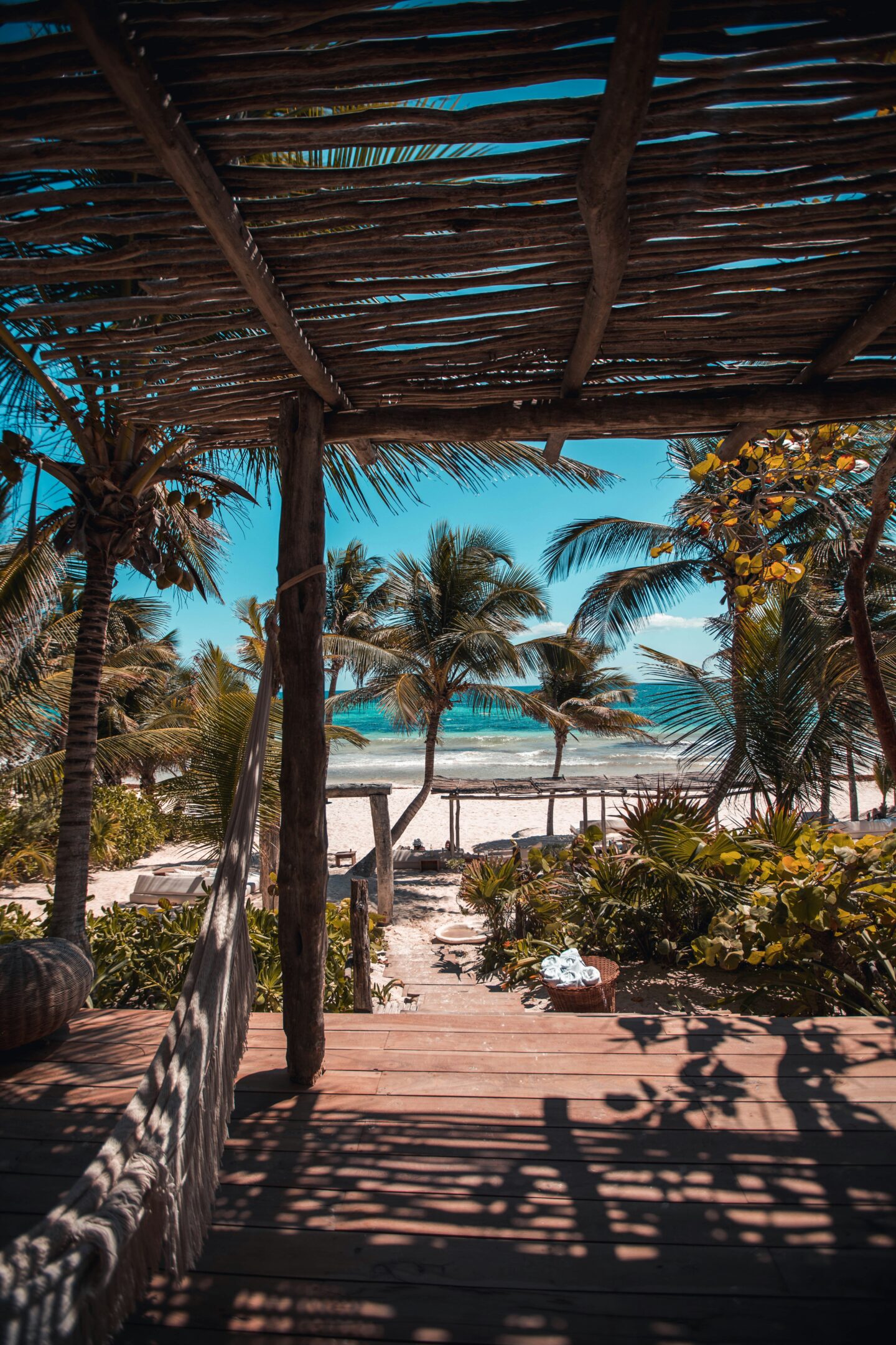 Tulum beach view from wooden jungle cabana terrace with palm trees tropical plants and turquoise ocean in Mexico