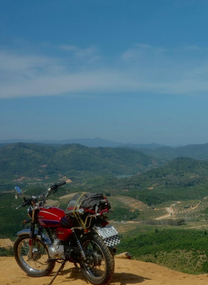 Motorbike parked at a scenic viewpoint overlooking the Vietnamese highlands with rolling hills and countryside views.