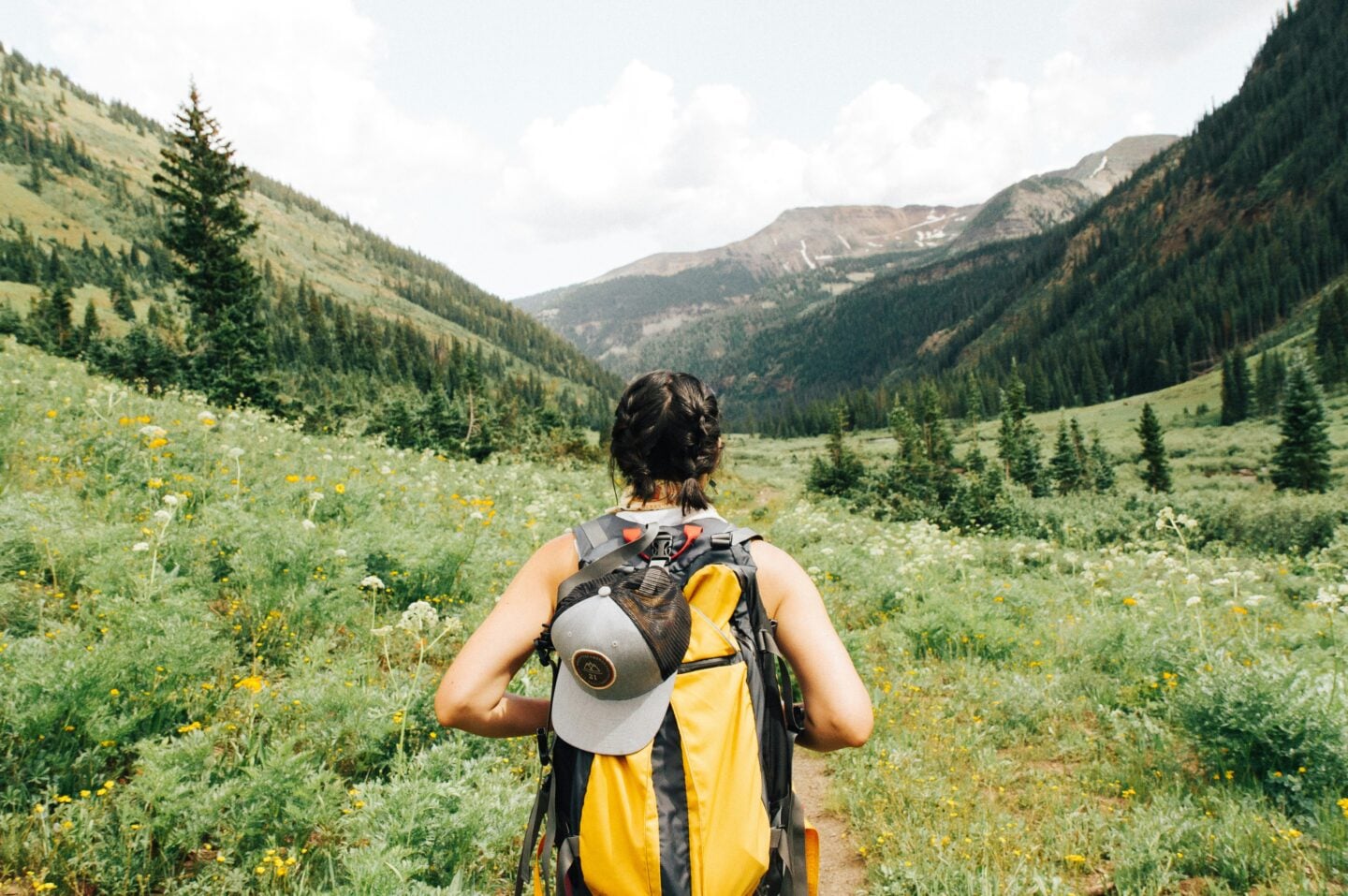 Hiker walking through scenic mountain trail with backpack, perfect setting for enjoying practical hiking lunch ideas in nature.