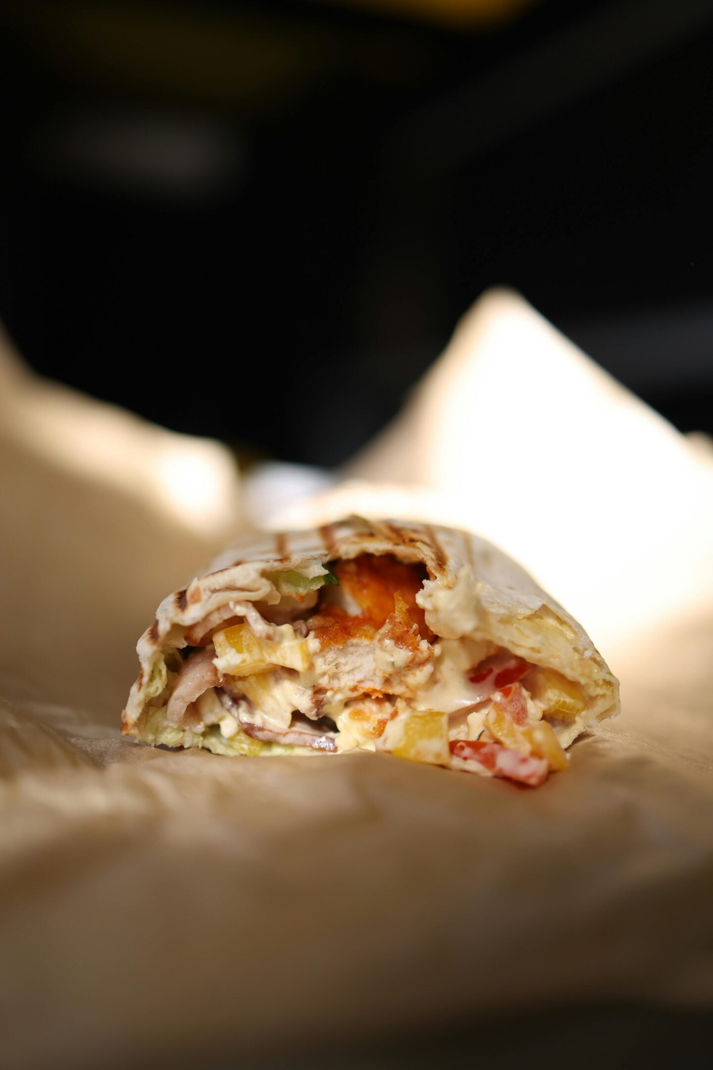 Chicken wrap with vegetables and creamy sauce on paper, easy and filling option for hiking lunch ideas on the go.