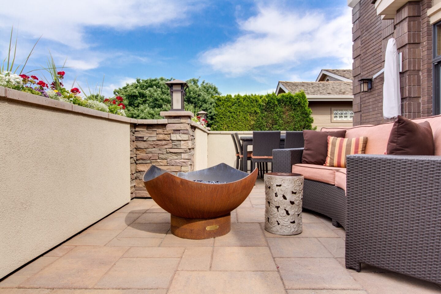 Patio seating area with outdoor fire pit, wicker furniture, and decorative stone accents in a modern backyard entertainment space.