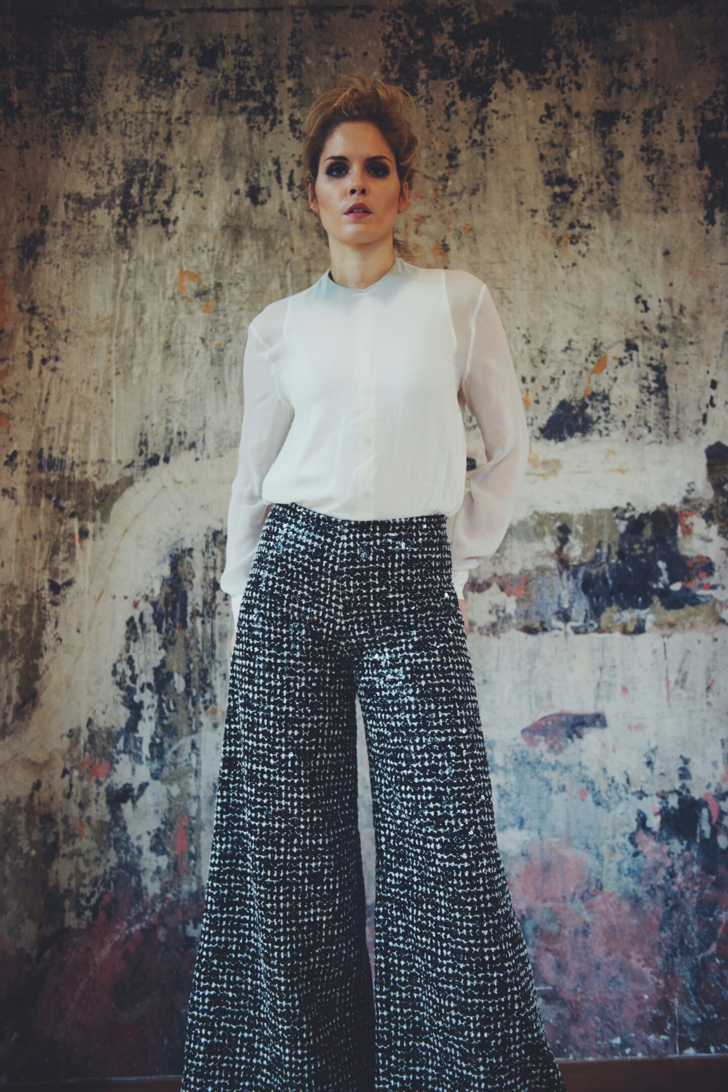 Woman wearing wide-leg black and white palazzo trousers paired with a white long-sleeve blouse.