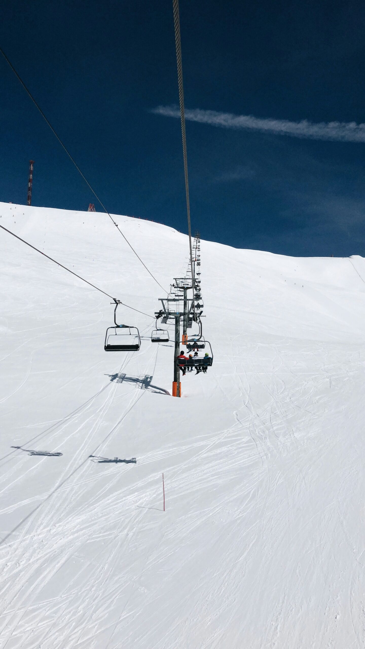 Chairlift carrying skiers up snowy slopes in Grandvalira, Andorra, under a clear blue winter sky.