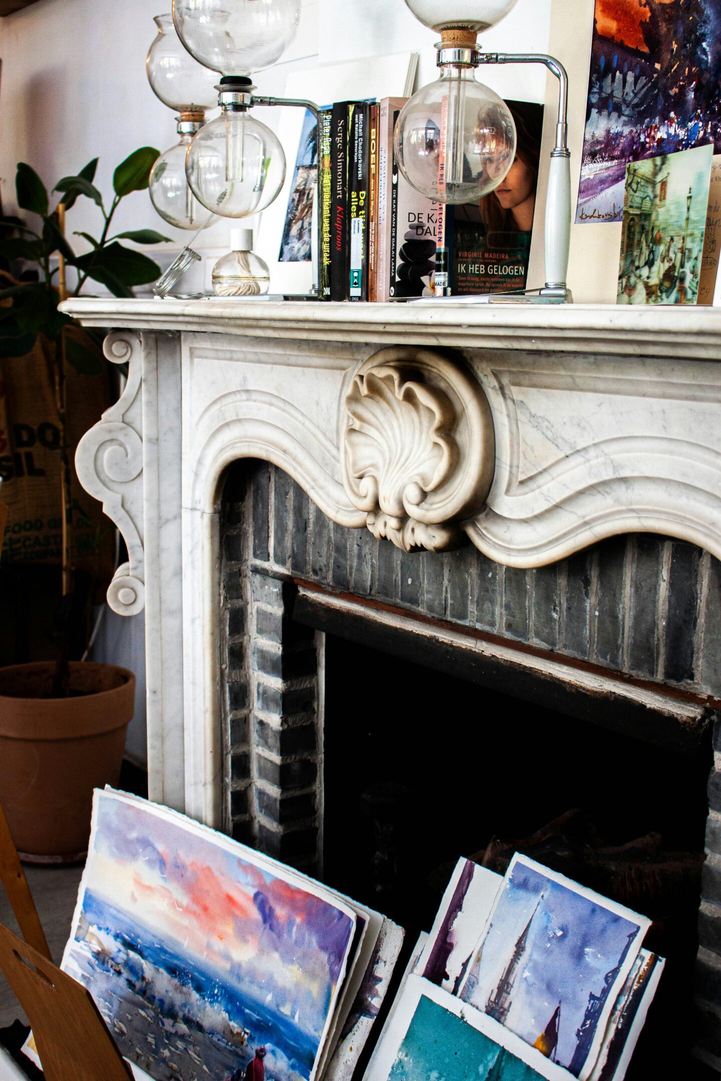 Decorative vintage marble fireplace with ornate carved details, styled with books, artwork, and modern lighting.