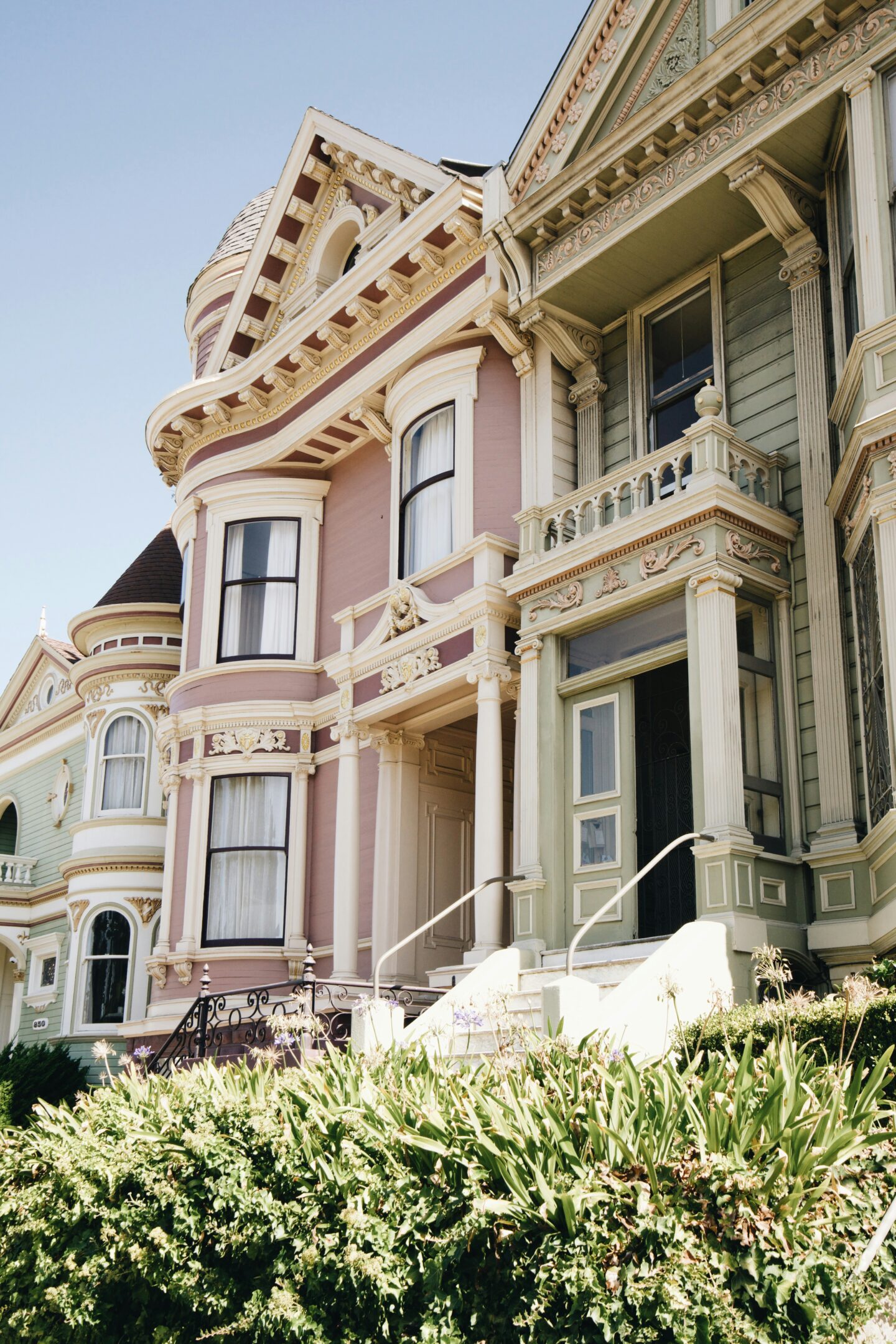 Exterior of a pastel Victorian-style house with ornate trim, bay windows, and original architectural details showcasing the charm of historic homes.